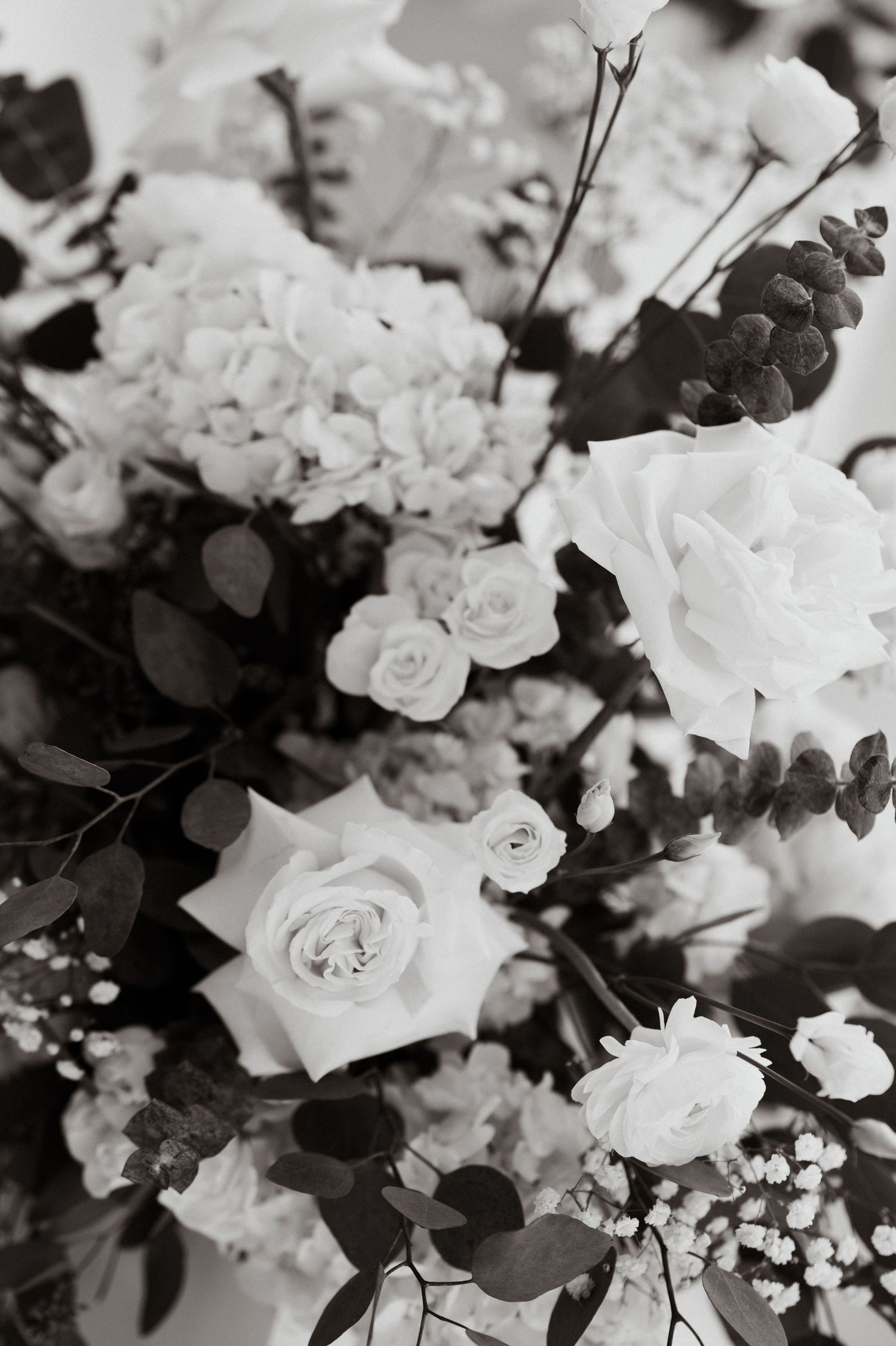 Detailed black and white close-up of white roses and mixed flowers in a wedding arrangement.