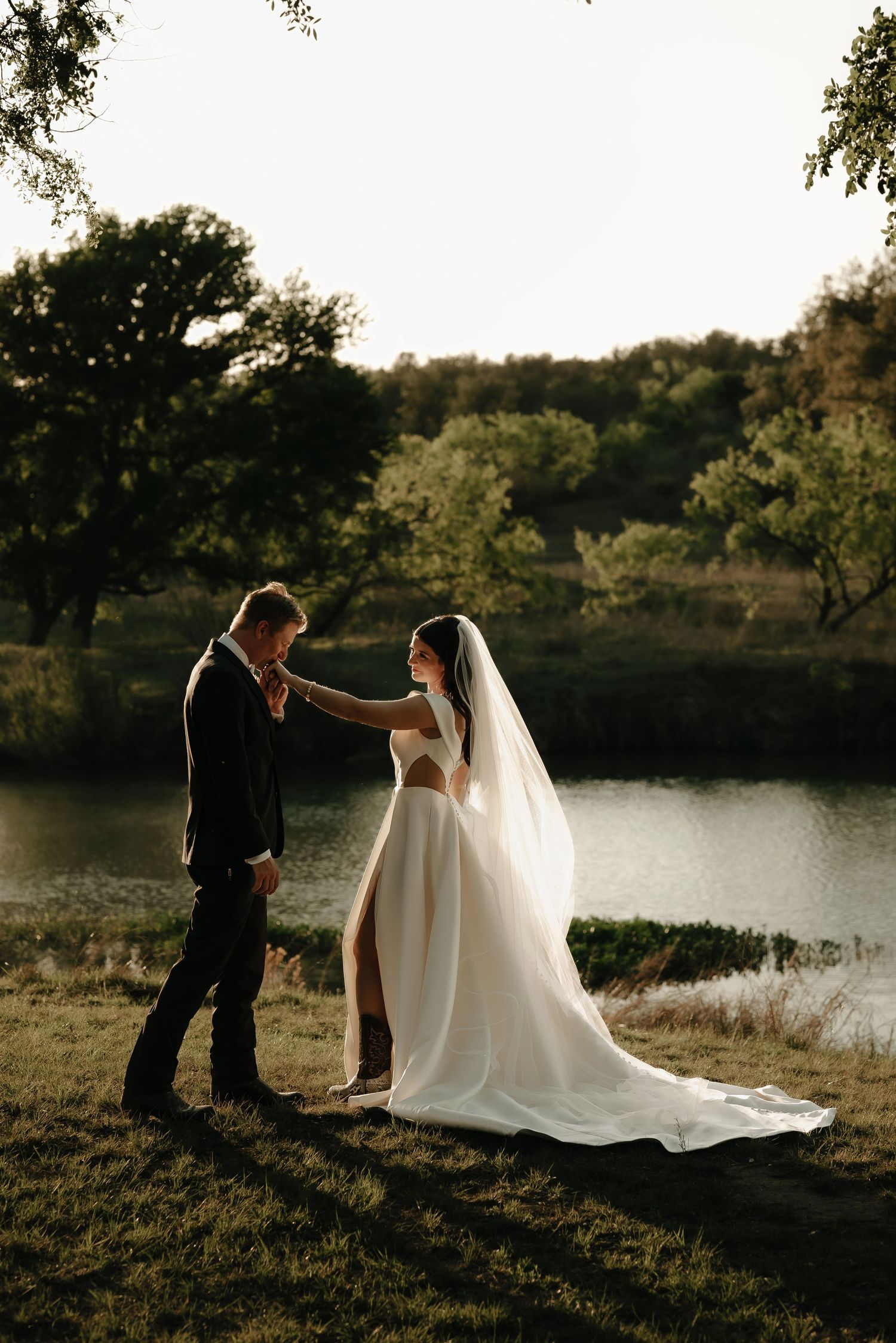 Romantic sunset wedding photos by a lake with couple in elegant attire.