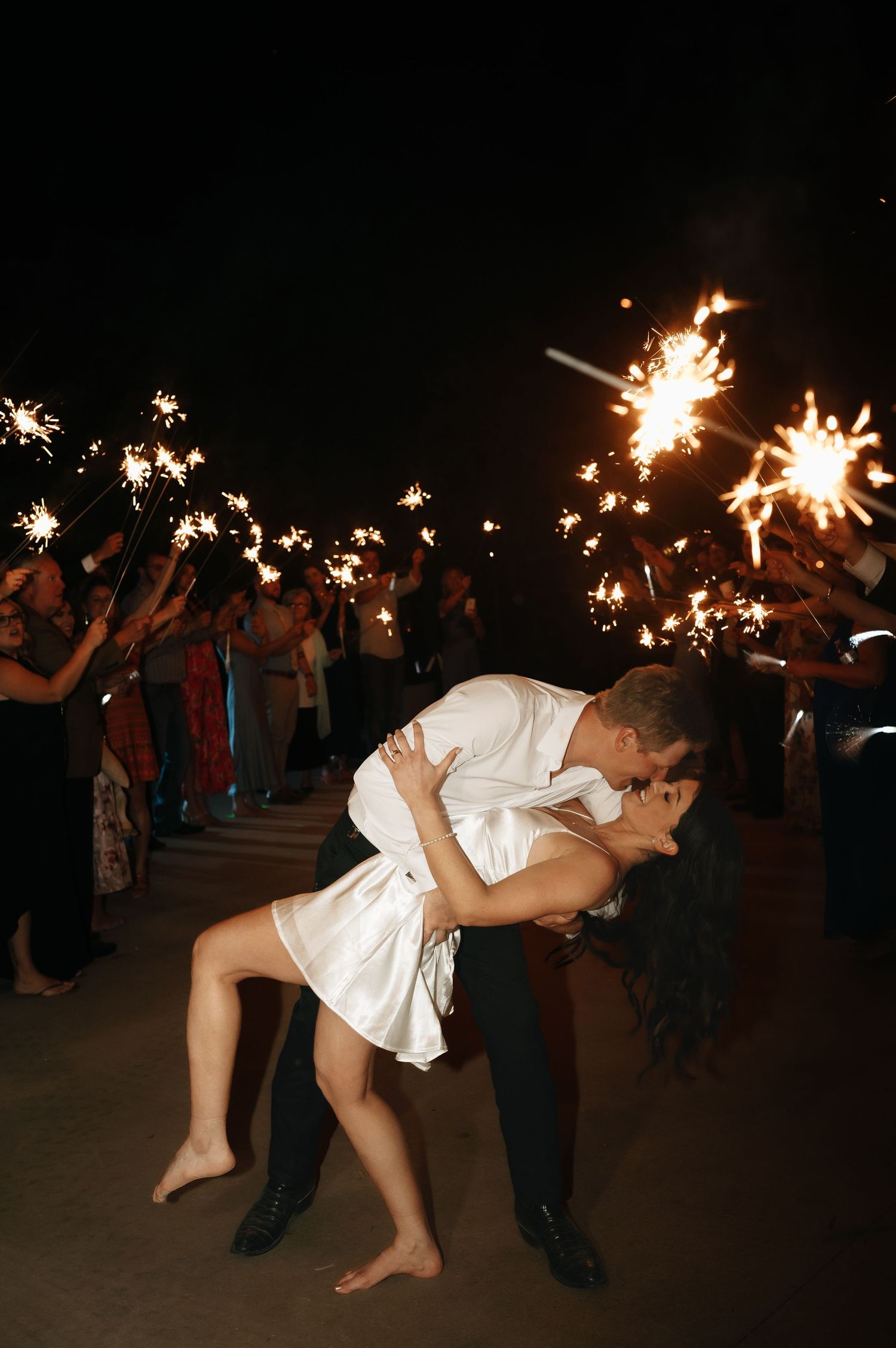 A dramatic wedding dance dip under sparklers during an evening celebration.