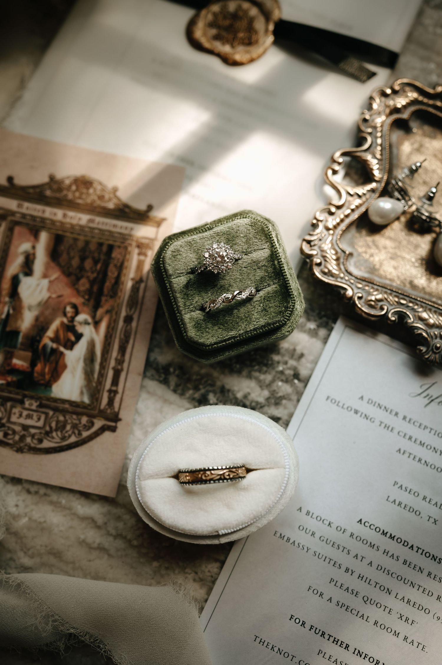 Wedding details including vintage frames, invitation suite, and rings in an elegant flat lay composition.