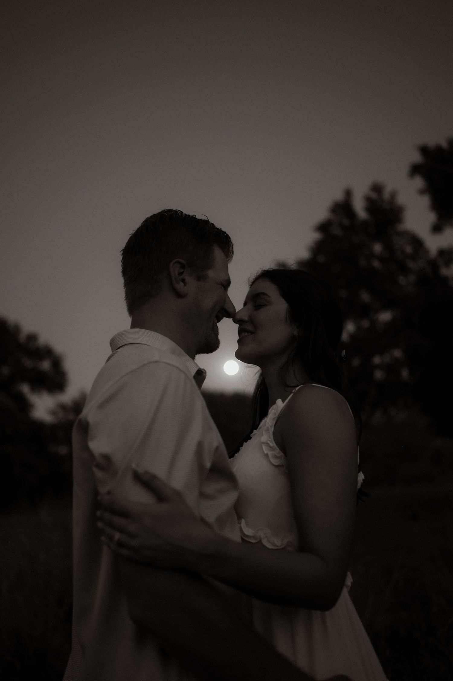 A romantic couple embraces in silhouette against a dusky evening sky.