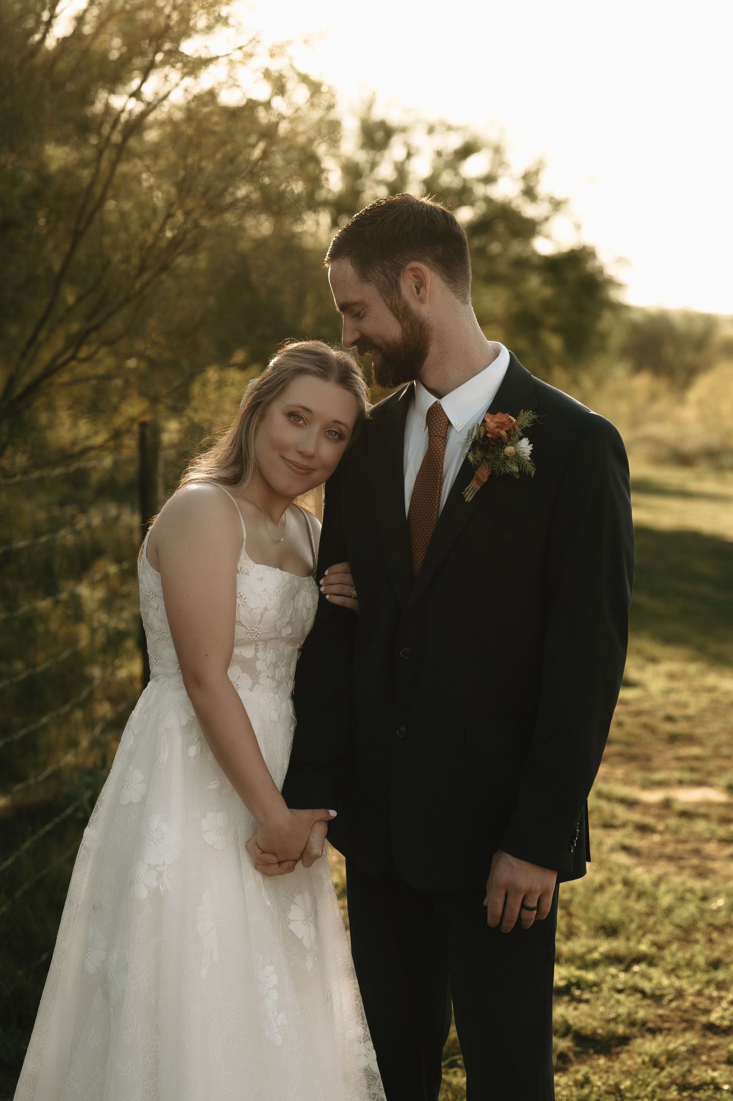 Romantic sunset portrait of couple in wedding attire on rolling hills.