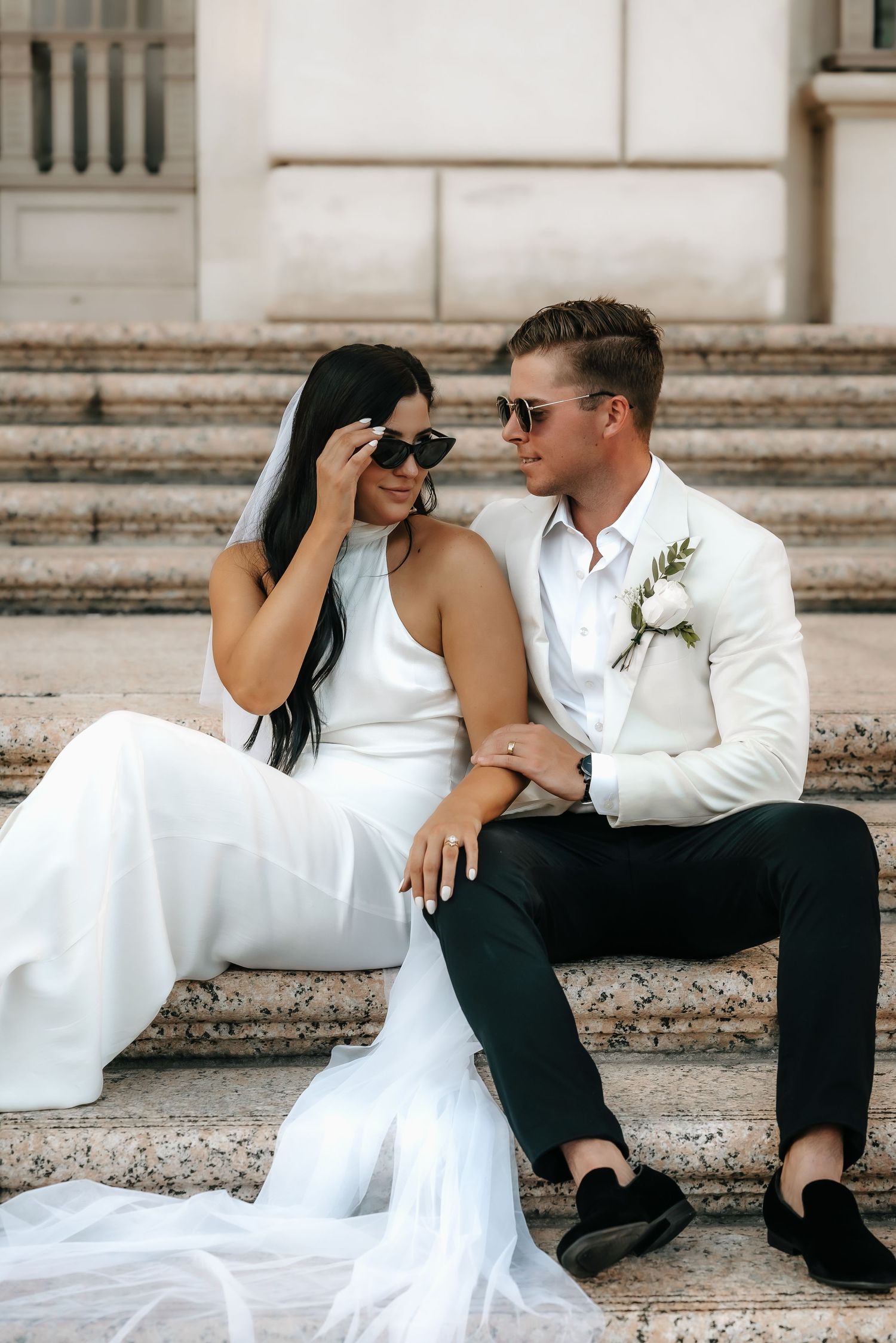 A wedding couple relaxes on stone steps in an artistic photo series.