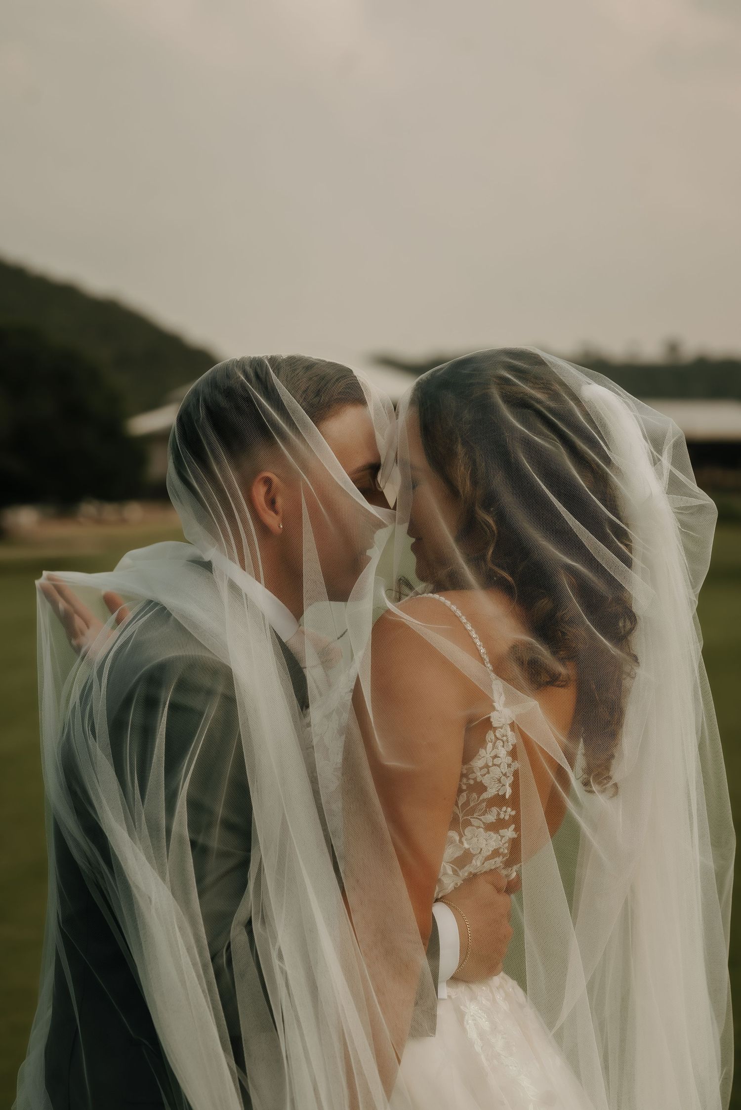 Intimate wedding moment captured through delicate white veils in soft focus.