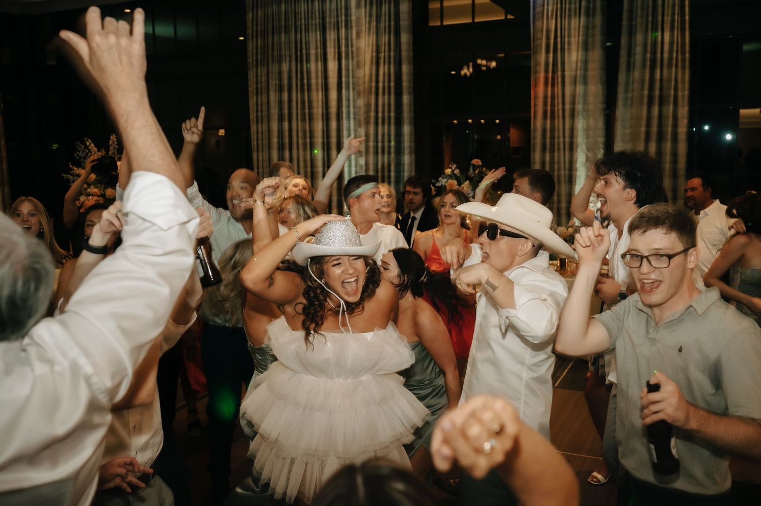 Lively wedding reception dance party with guests celebrating on a crowded dance floor.