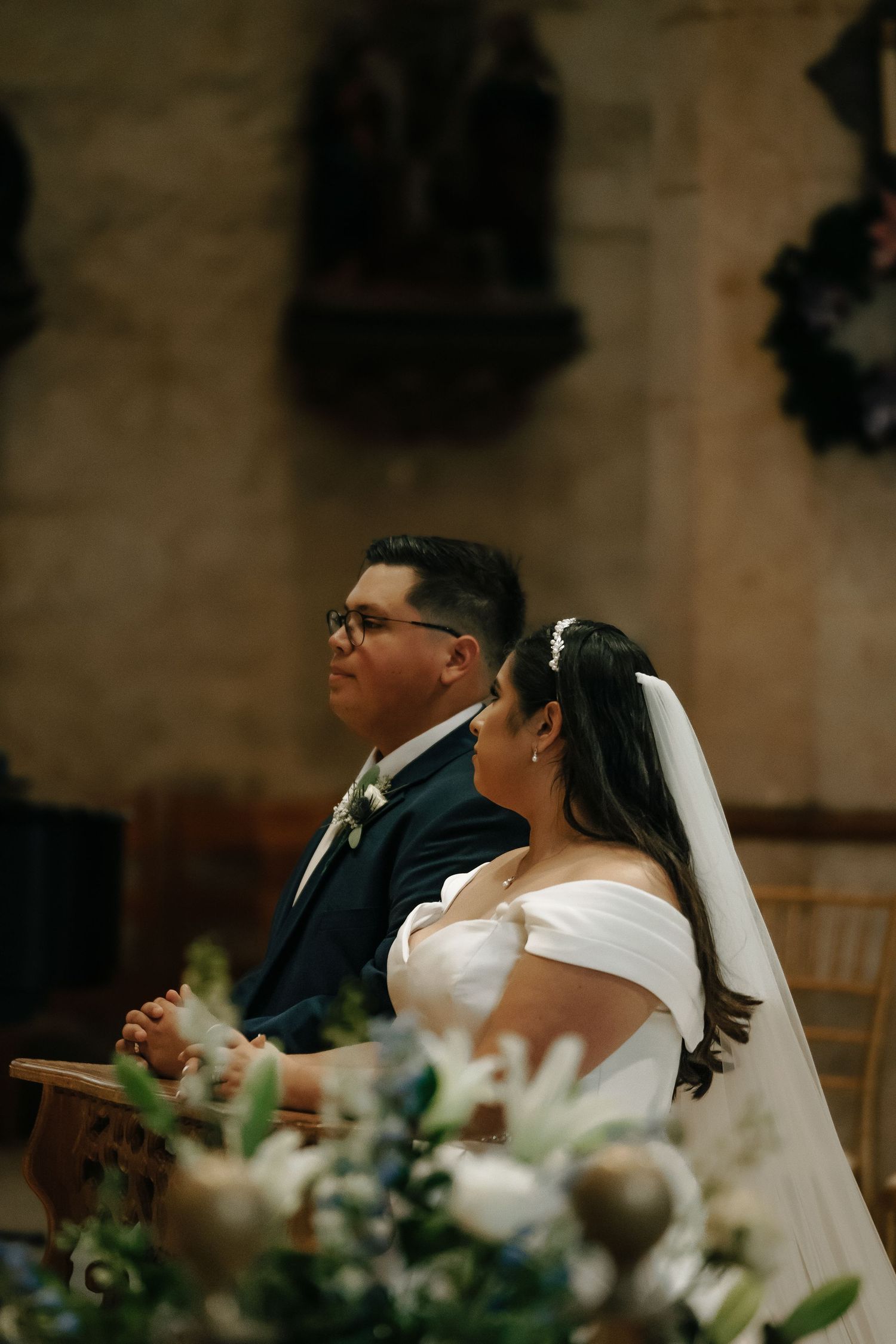 Elegant church wedding ceremony with white floral decorations and guests seated in wooden pews.