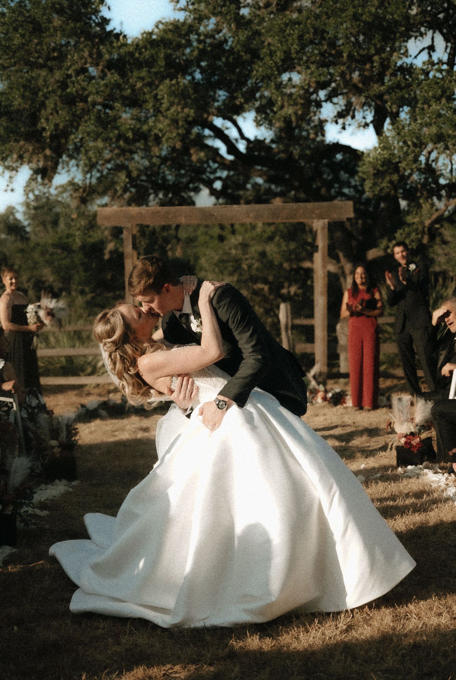 Dramatic wedding couple poses against natural landscape during outdoor ceremony.