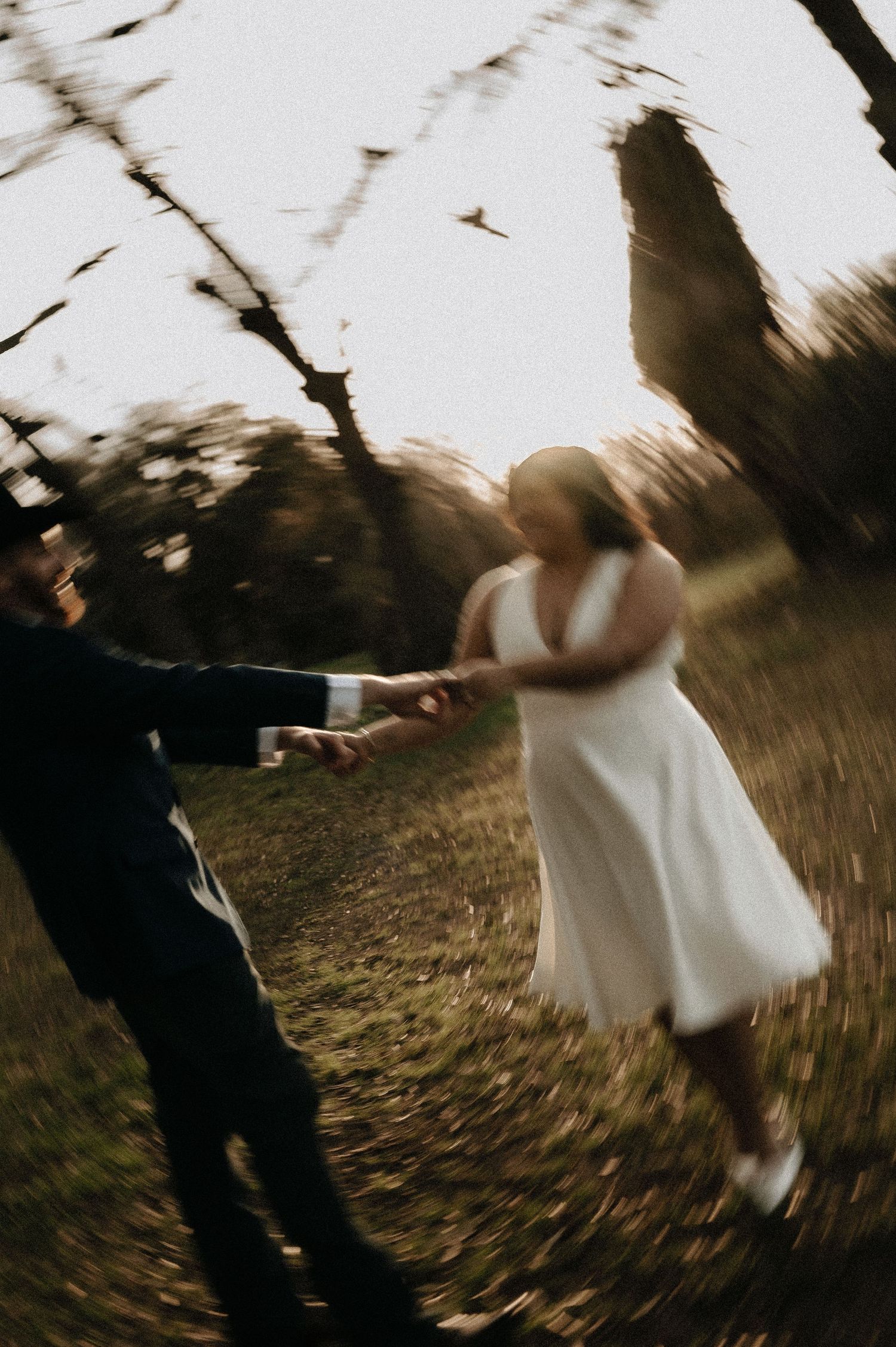 A spinning motion blur captures a couple dancing outdoors in formal attire.