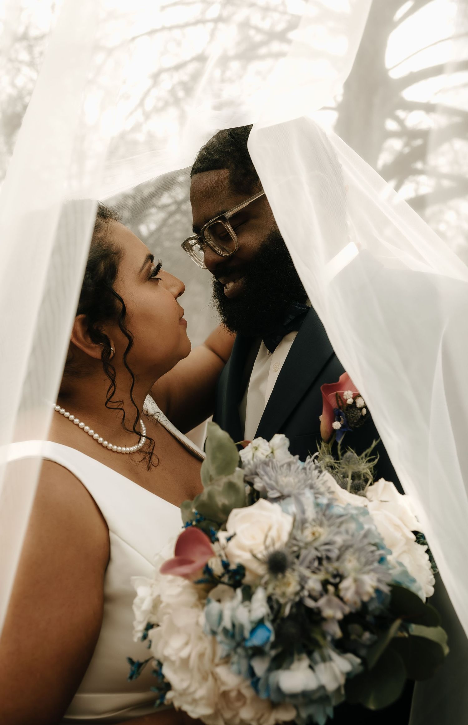 Intimate wedding portrait with soft lighting and delicate white and blue bouquet.