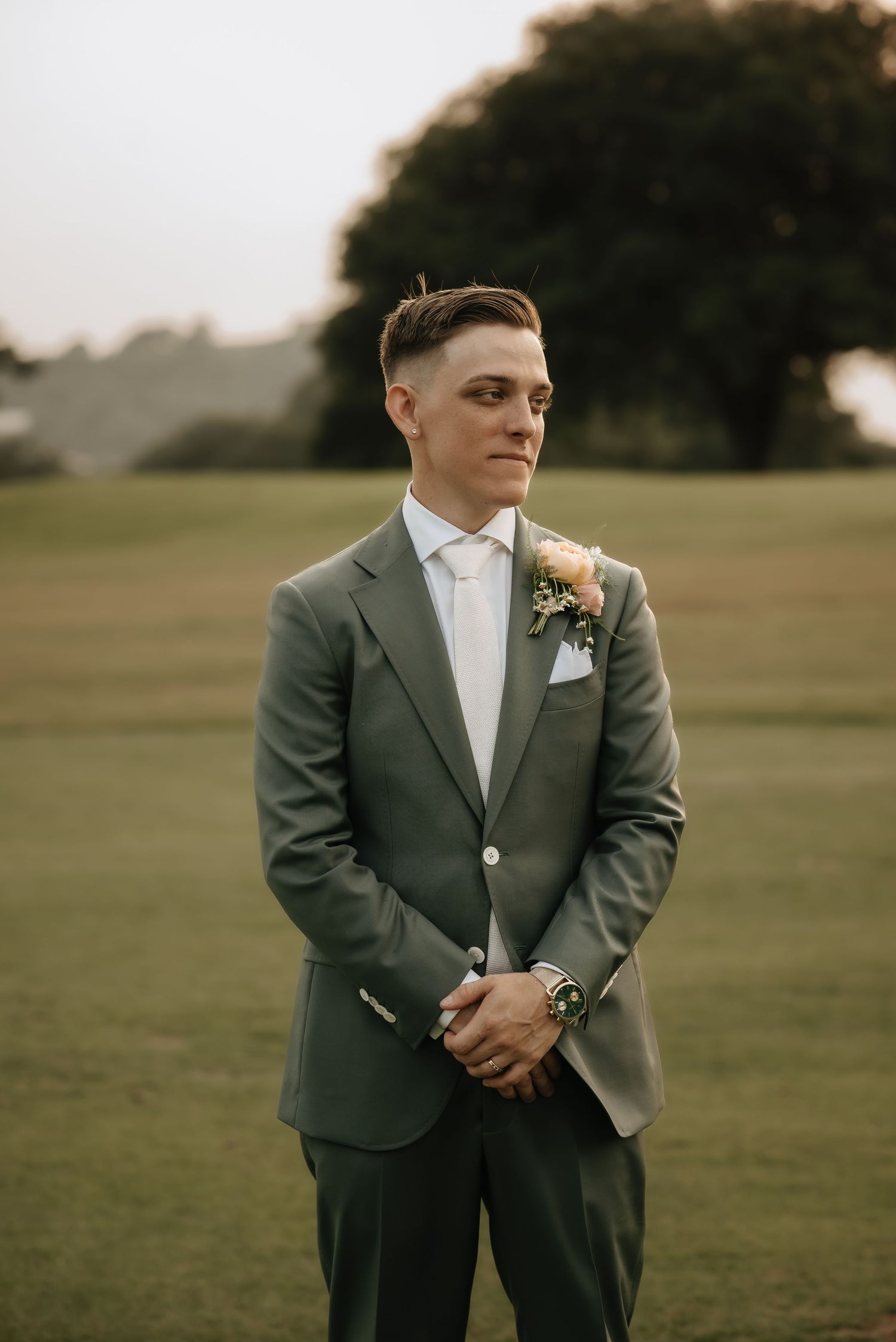 Wedding portrait series showing someone in a dark suit and boutonniere against an outdoor backdrop.