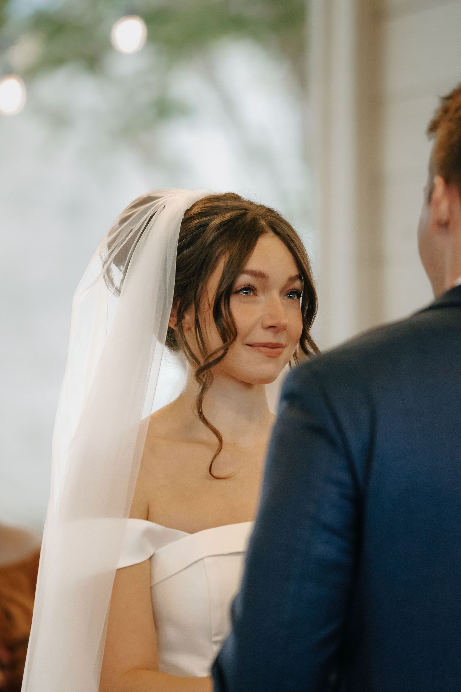 Close-up sequence of bride in white strapless dress with flowing veil during ceremony.