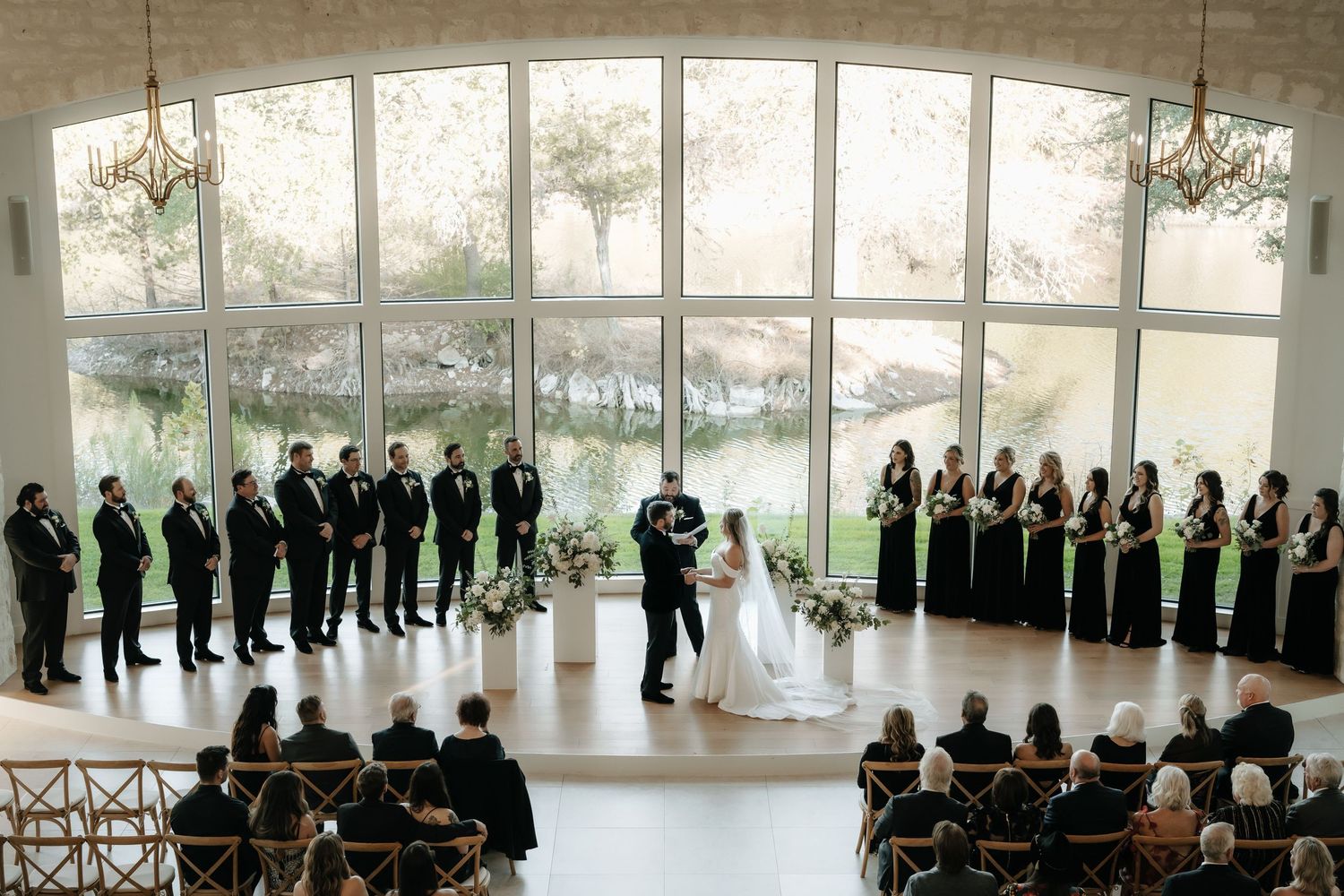 Panoramic view of a wedding ceremony setup with guests lined up in a modern white venue.