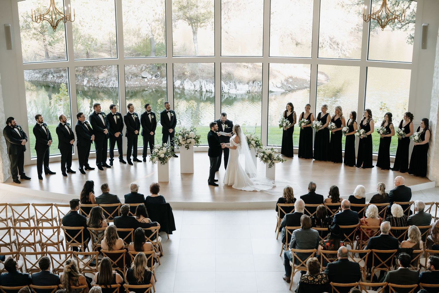 Wide view of an elegant indoor wedding ceremony with guests seated in rows.