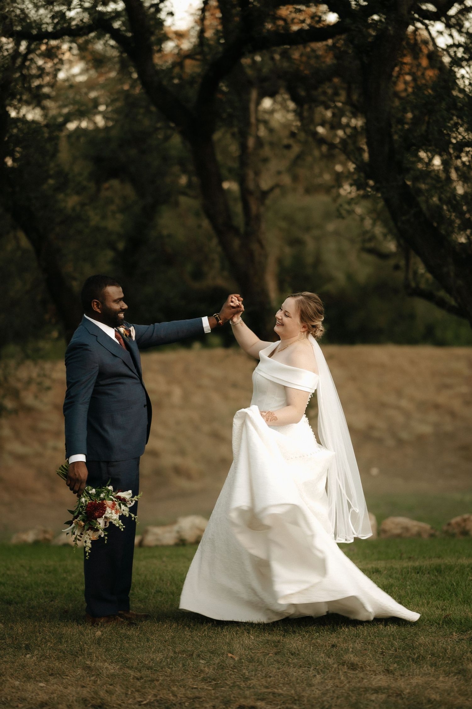 Couple holds hands and spins during outdoor wedding portrait session.