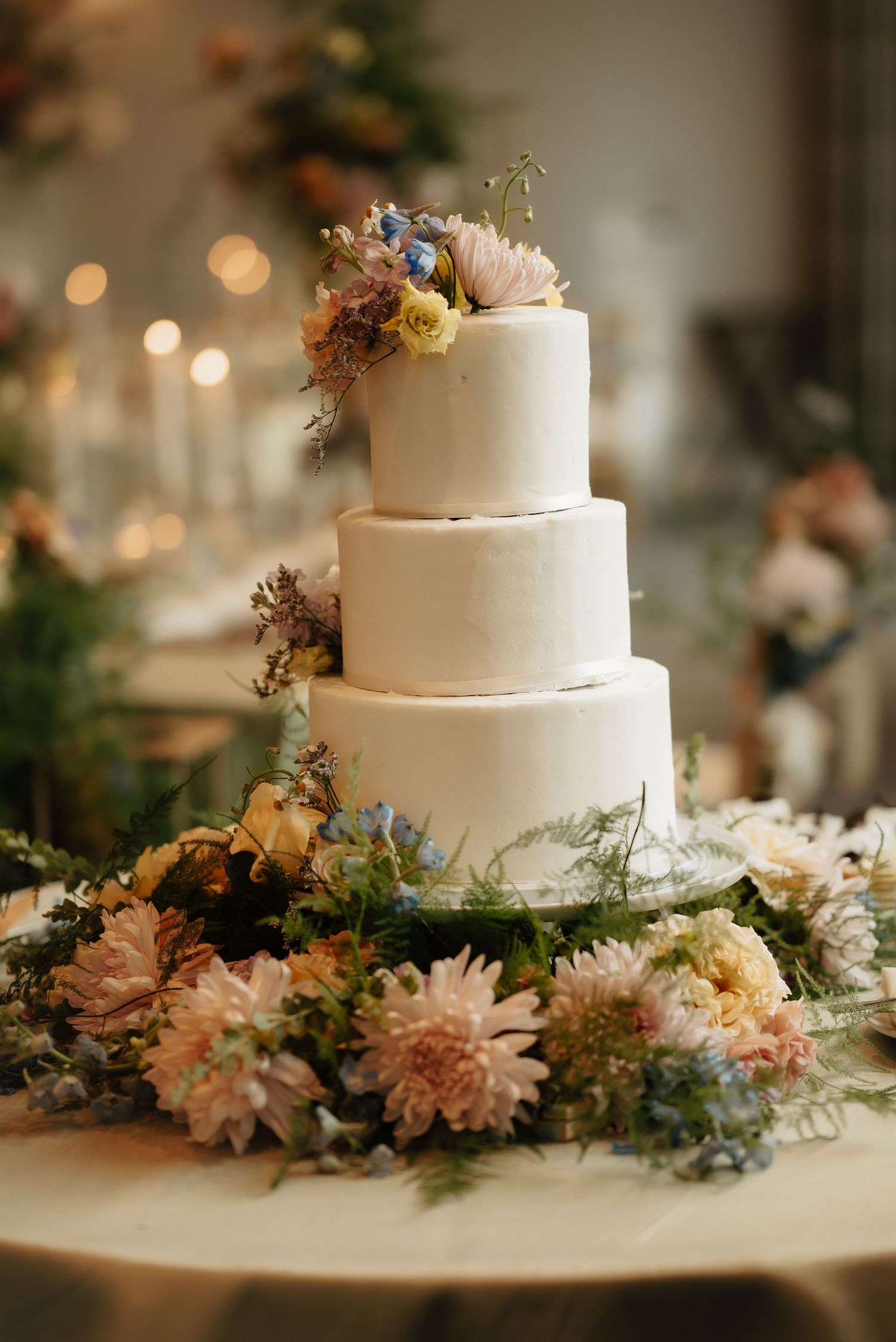 White tiered wedding cake decorated with delicate peach and pink flowers.