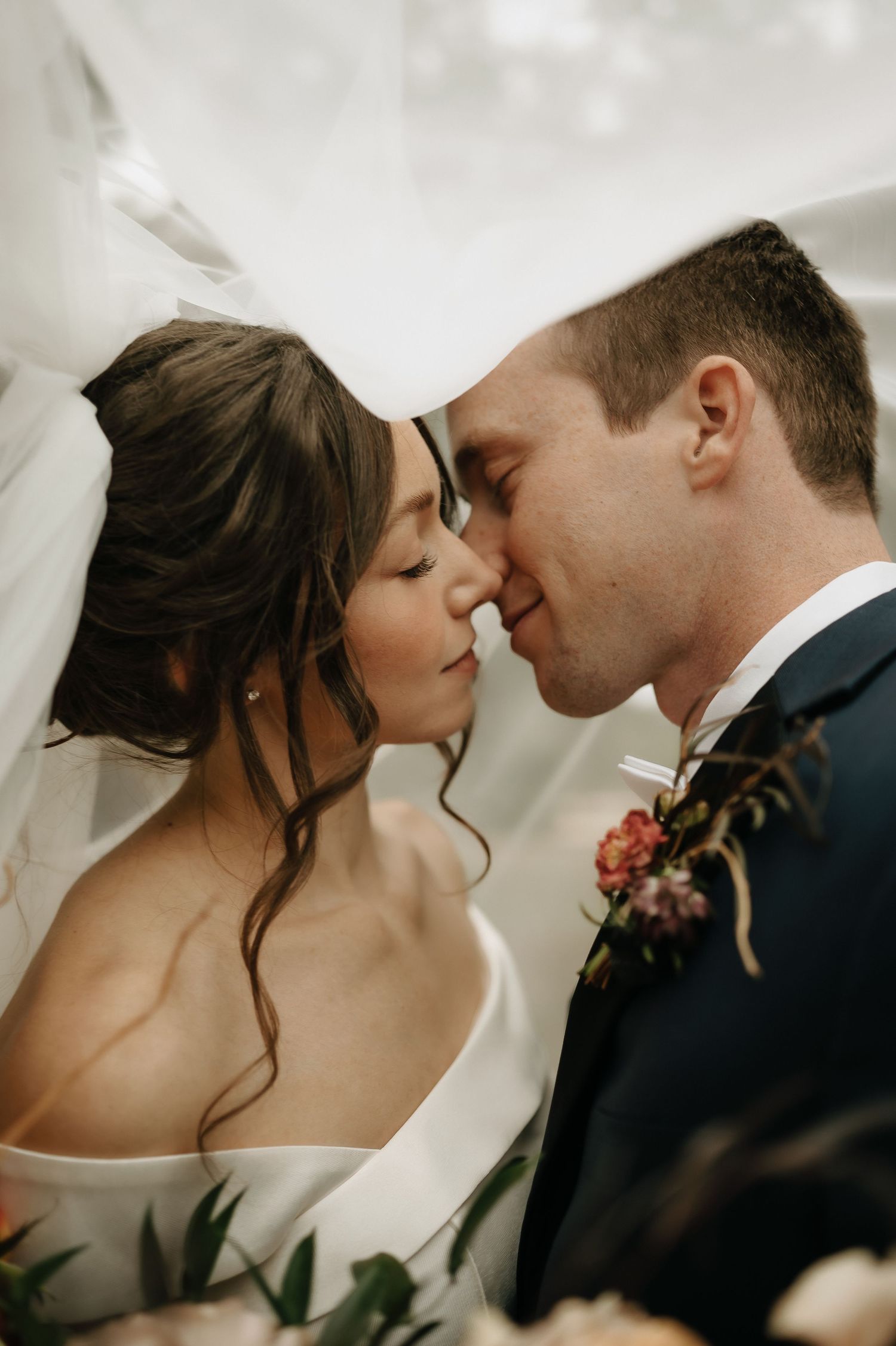 Intimate wedding portrait showing tender moment between newlyweds with soft lighting and romantic styling.