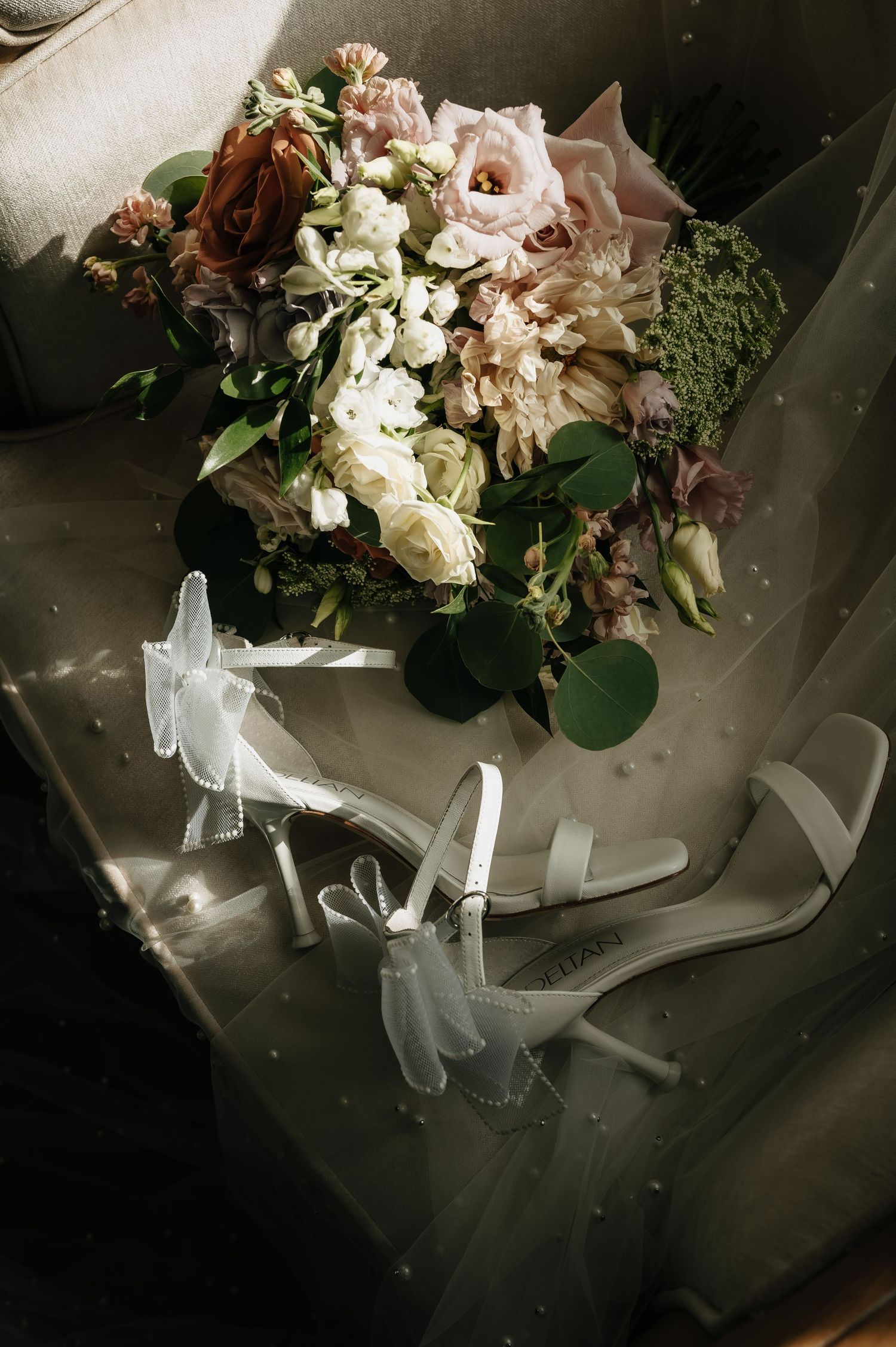Elegant wedding bouquet with white roses and delicate ribbons arranged on a dark surface.