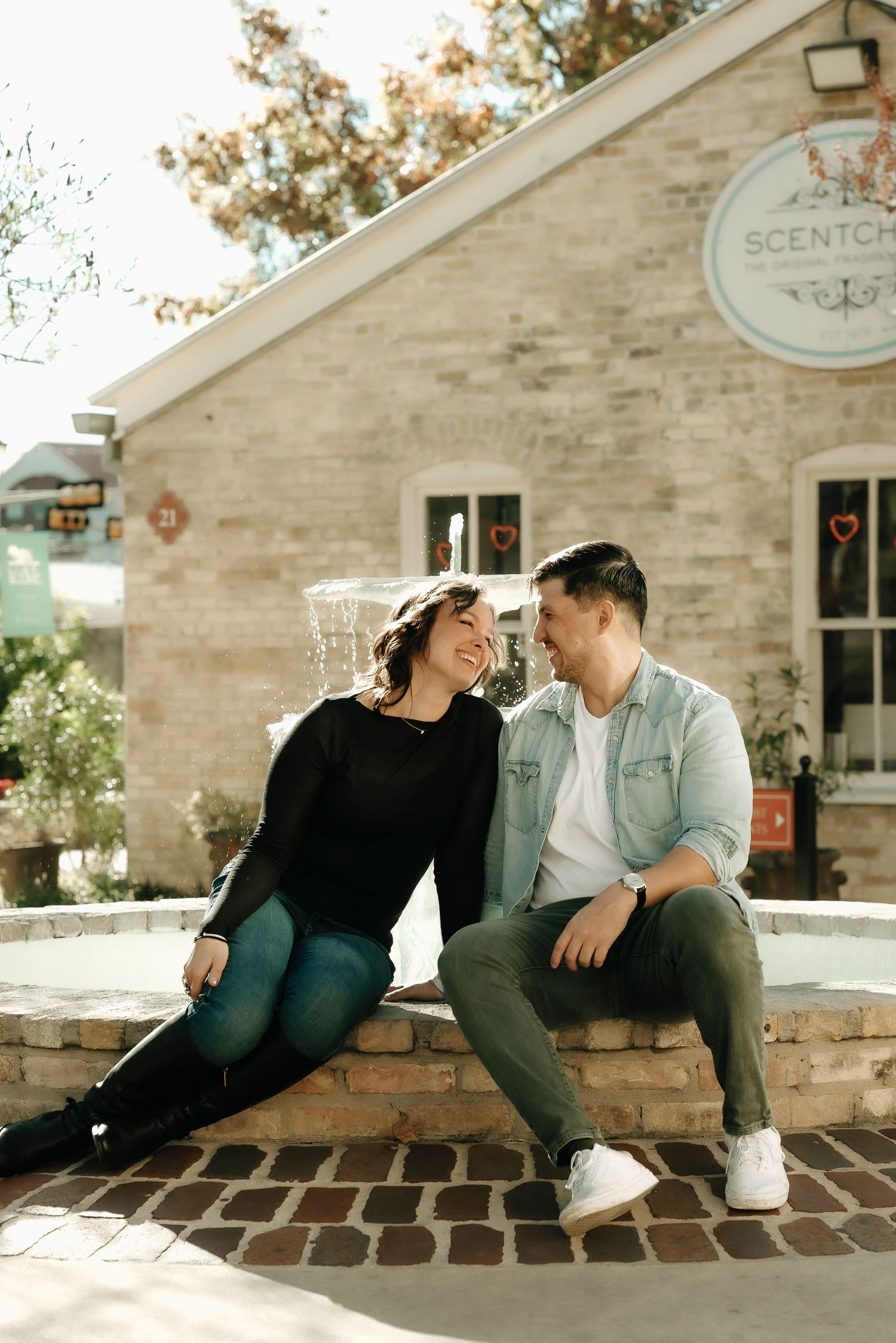 Couple sitting together on brick steps outside stone building.
