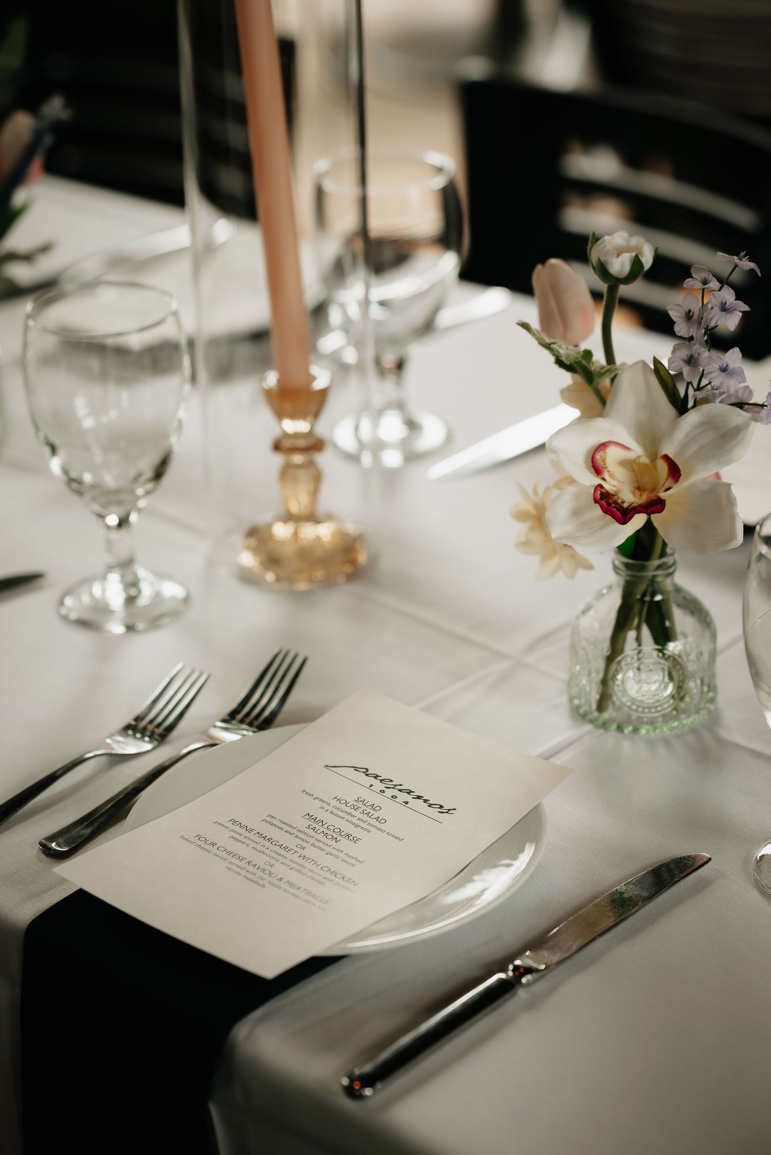 Elegant wedding reception table setting with menu cards and floral centerpieces.