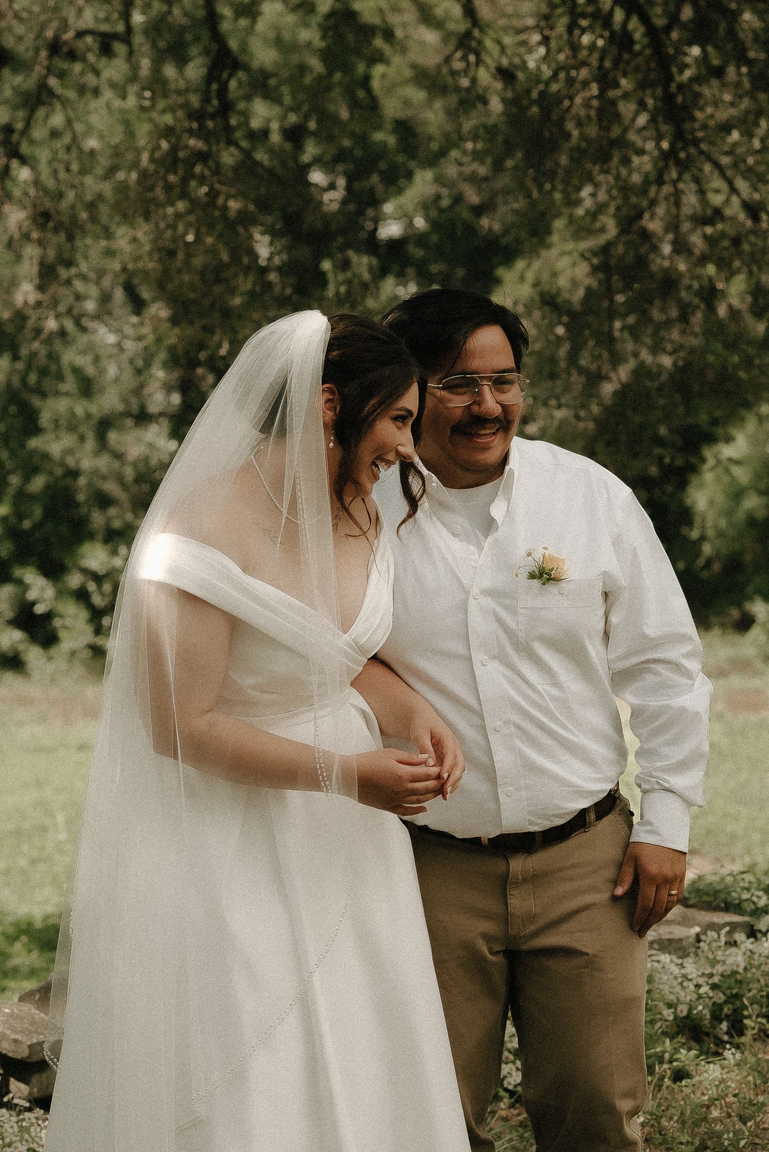 A couple shares joyful moments outdoors during a wedding photoshoot in a natural setting.