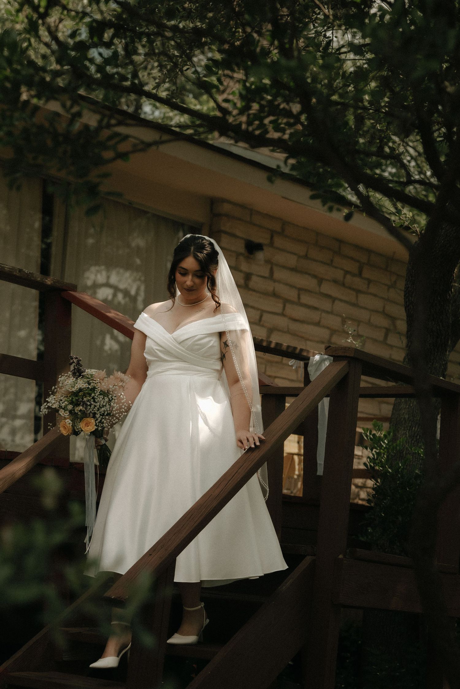 Elegant bridal portrait in white dress against rustic brick wall setting.