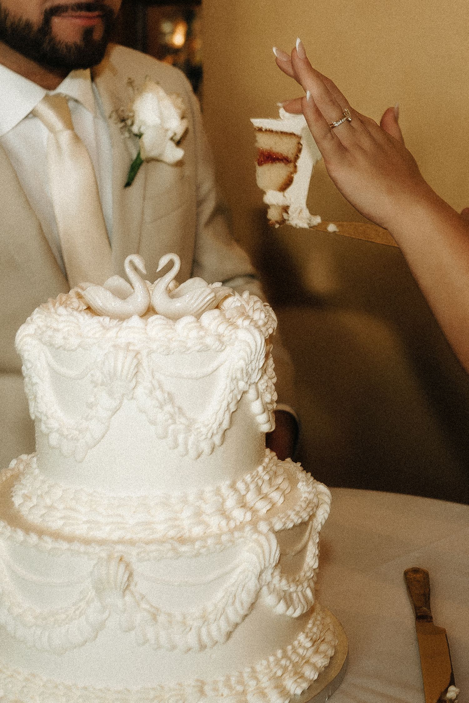 Elegant white wedding cake with delicate piped details and ruffled tiers being decorated.
