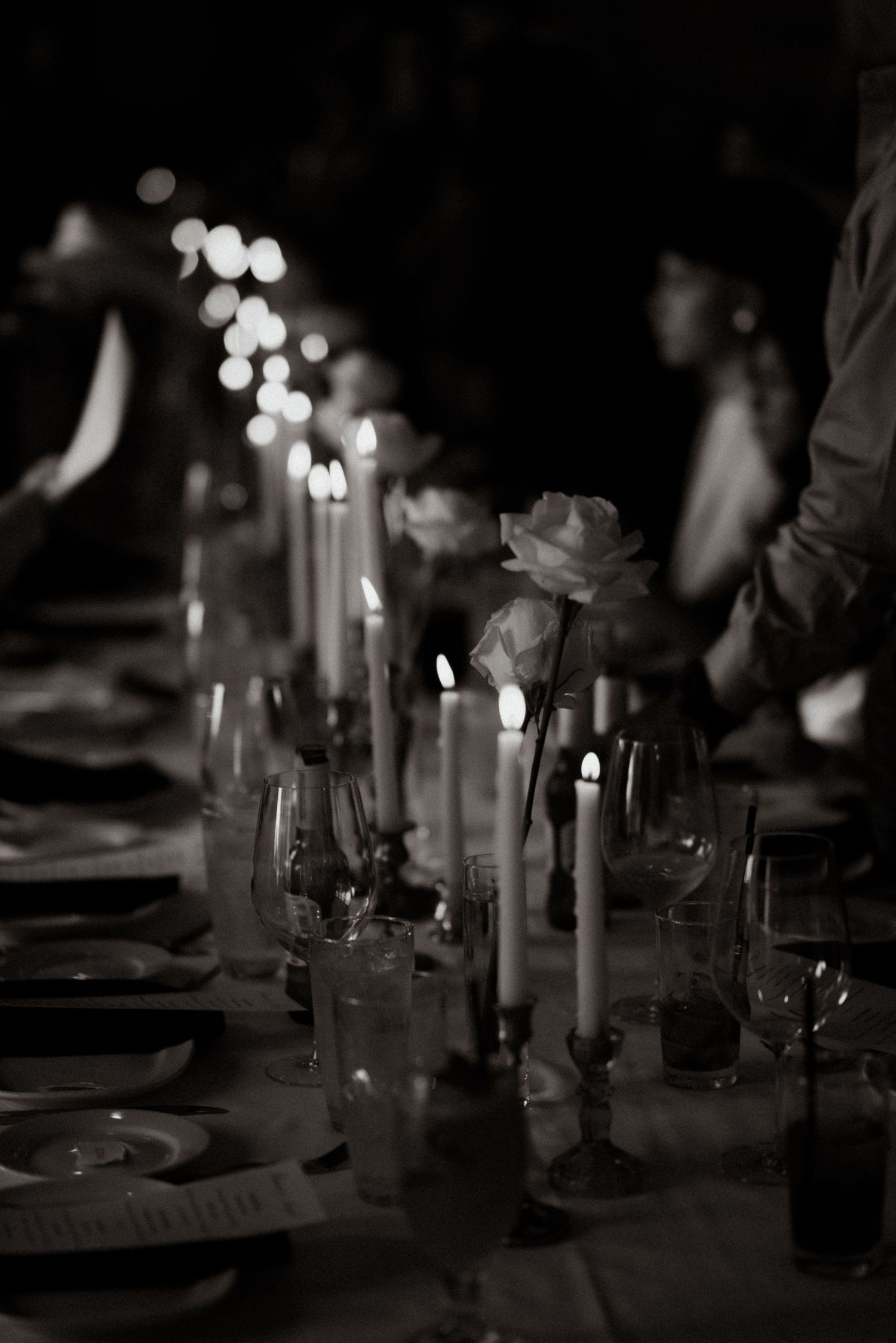 Candlelit wedding reception table setting captured in moody black and white photography.