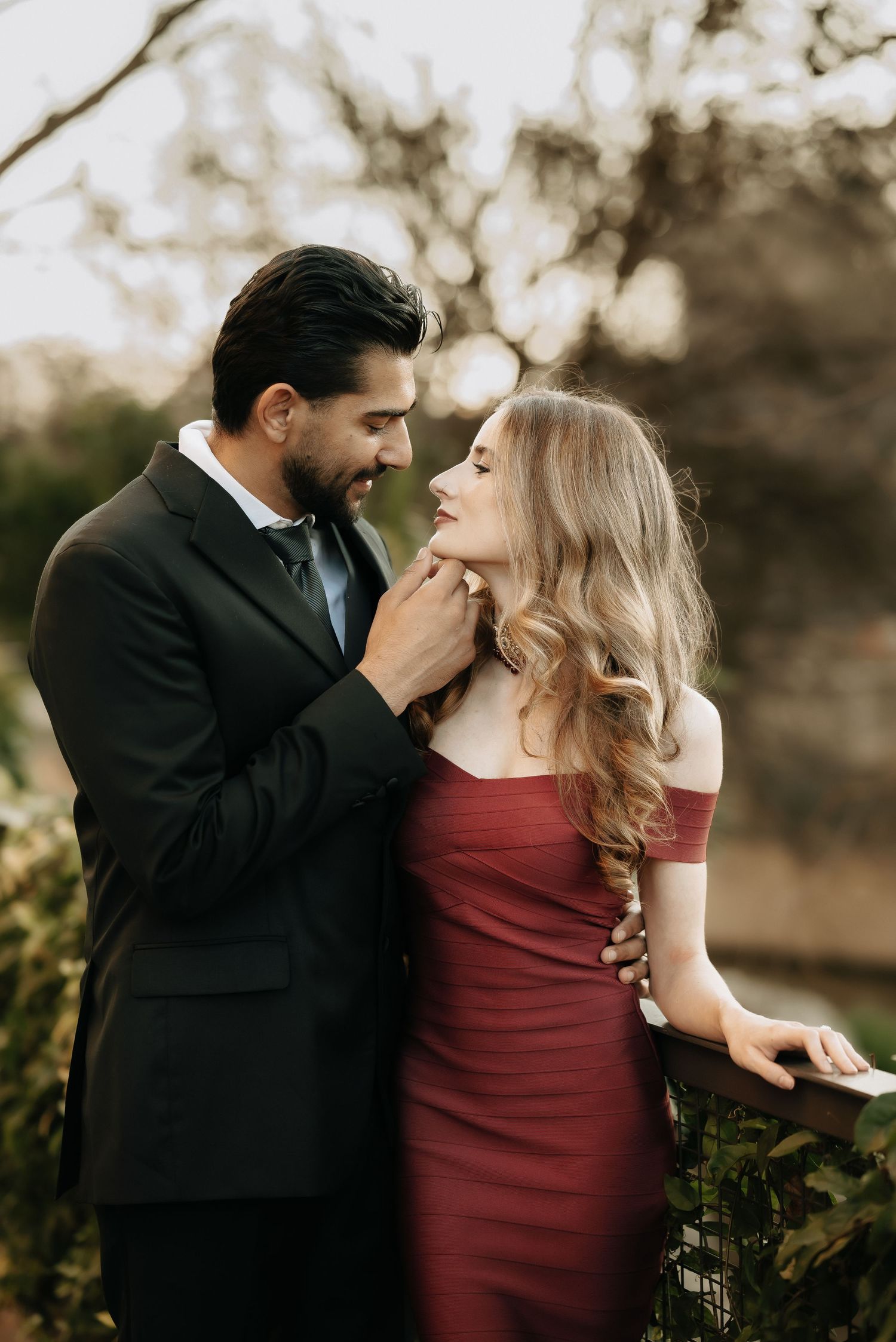 Romantic couple in formal attire sharing an intimate moment outdoors.