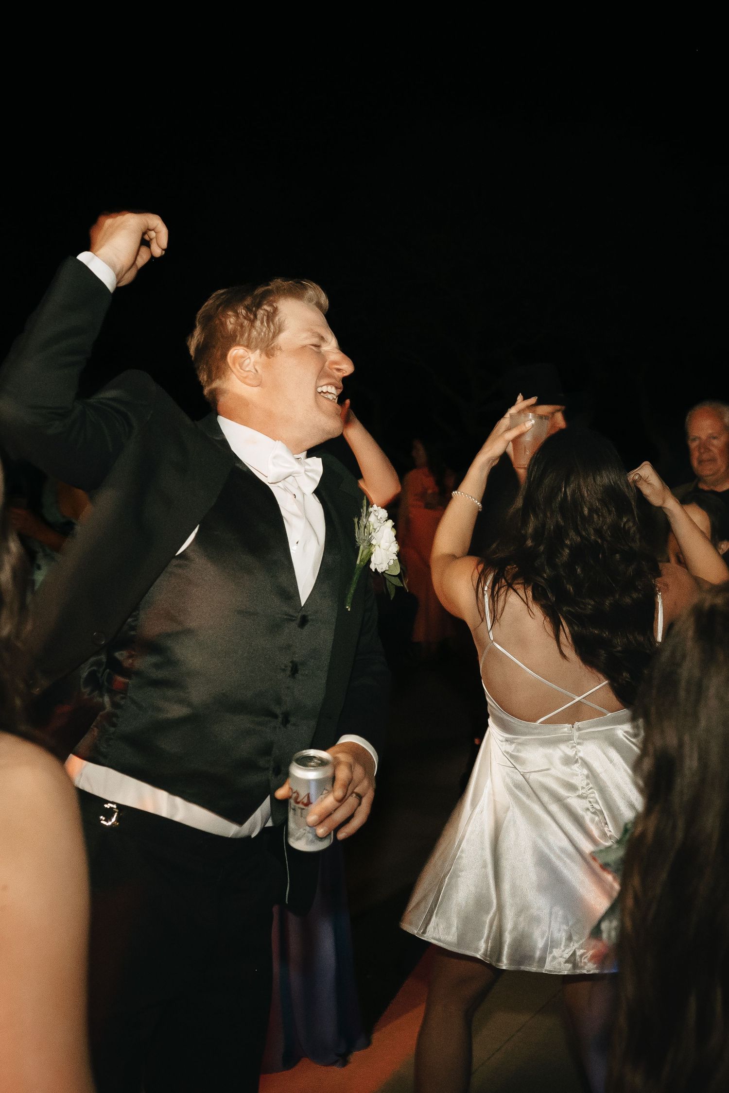 Wedding reception dance floor captures energetic moments between couples in formal attire.