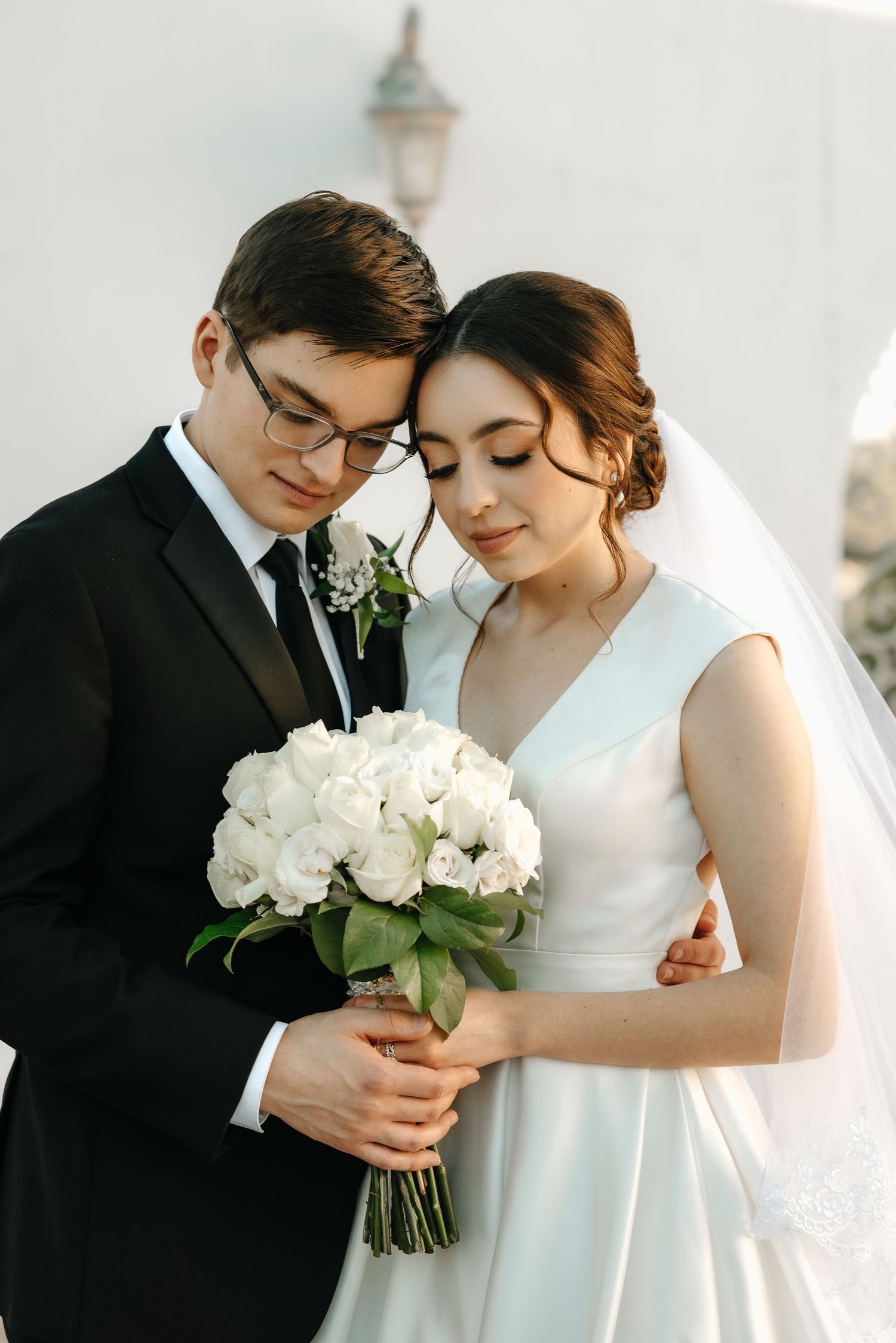 Romantic wedding portraits with white rose bouquet and elegant white dress.