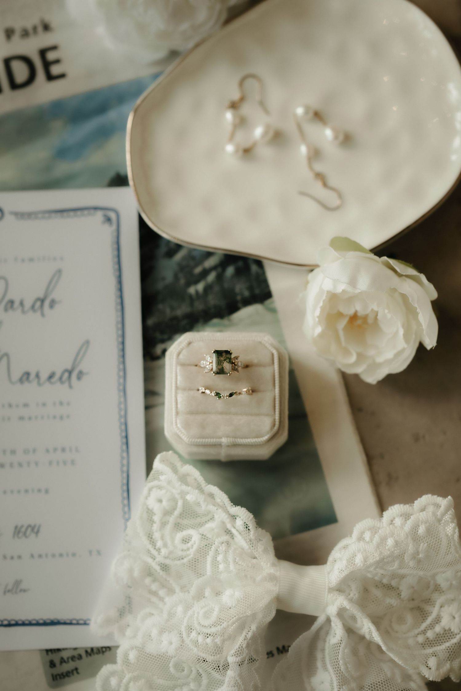 Wedding details featuring delicate white ring boxes and elegant invitation suite.