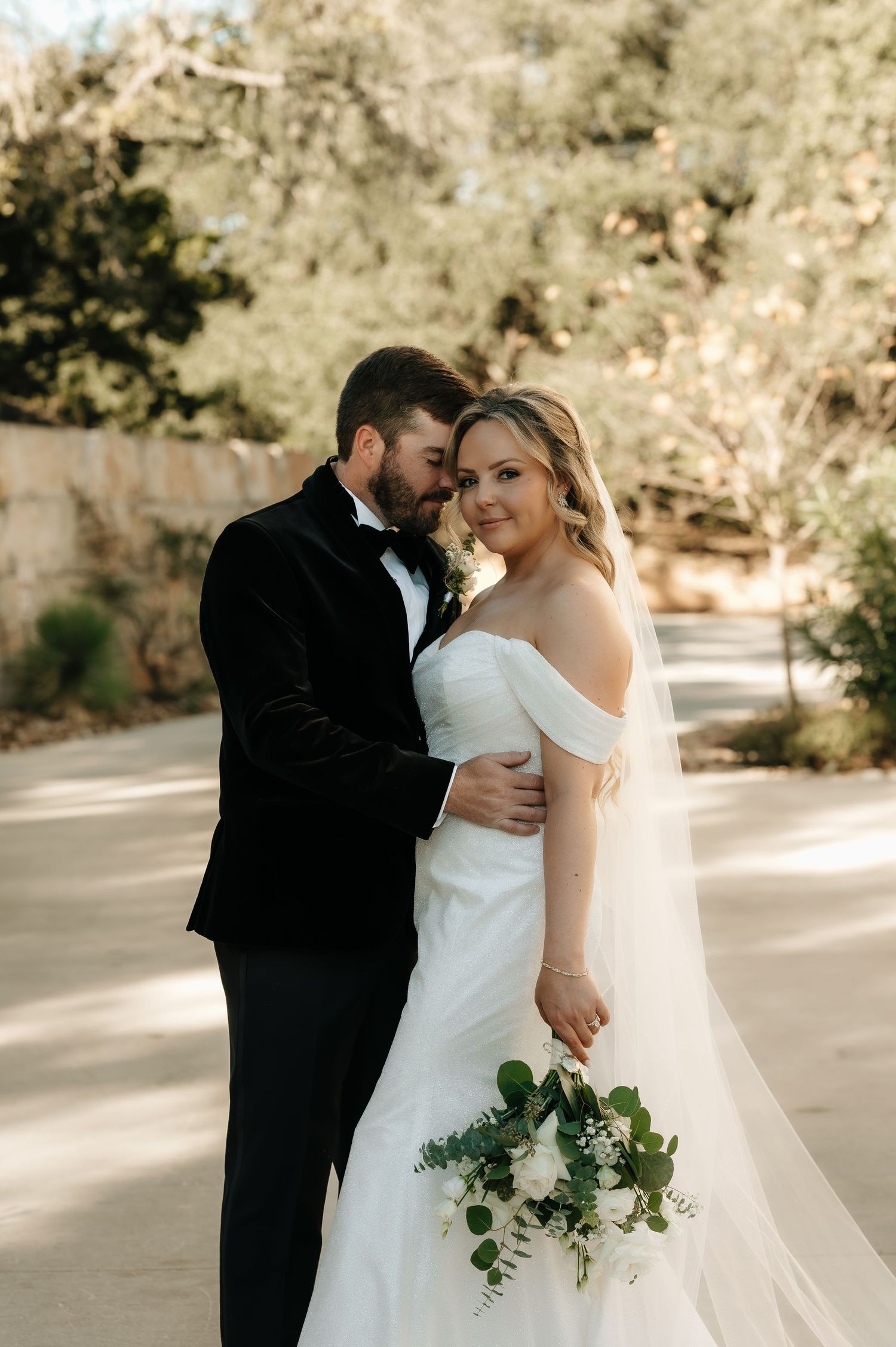 Romantic outdoor wedding portraits in soft natural lighting with flowing white dress and bouquet.