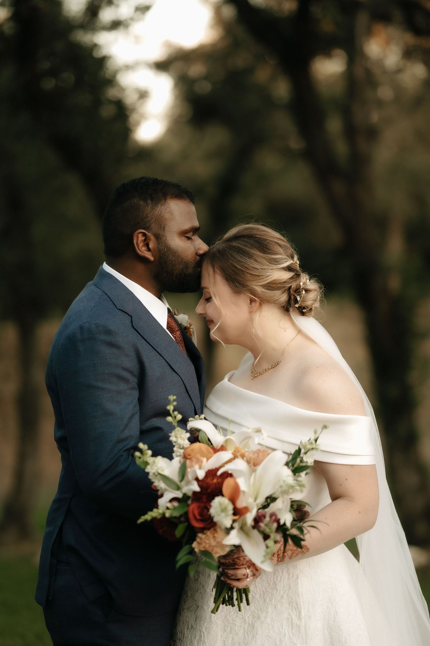 Intimate wedding moment captured with couple holding a colorful autumn bouquet.