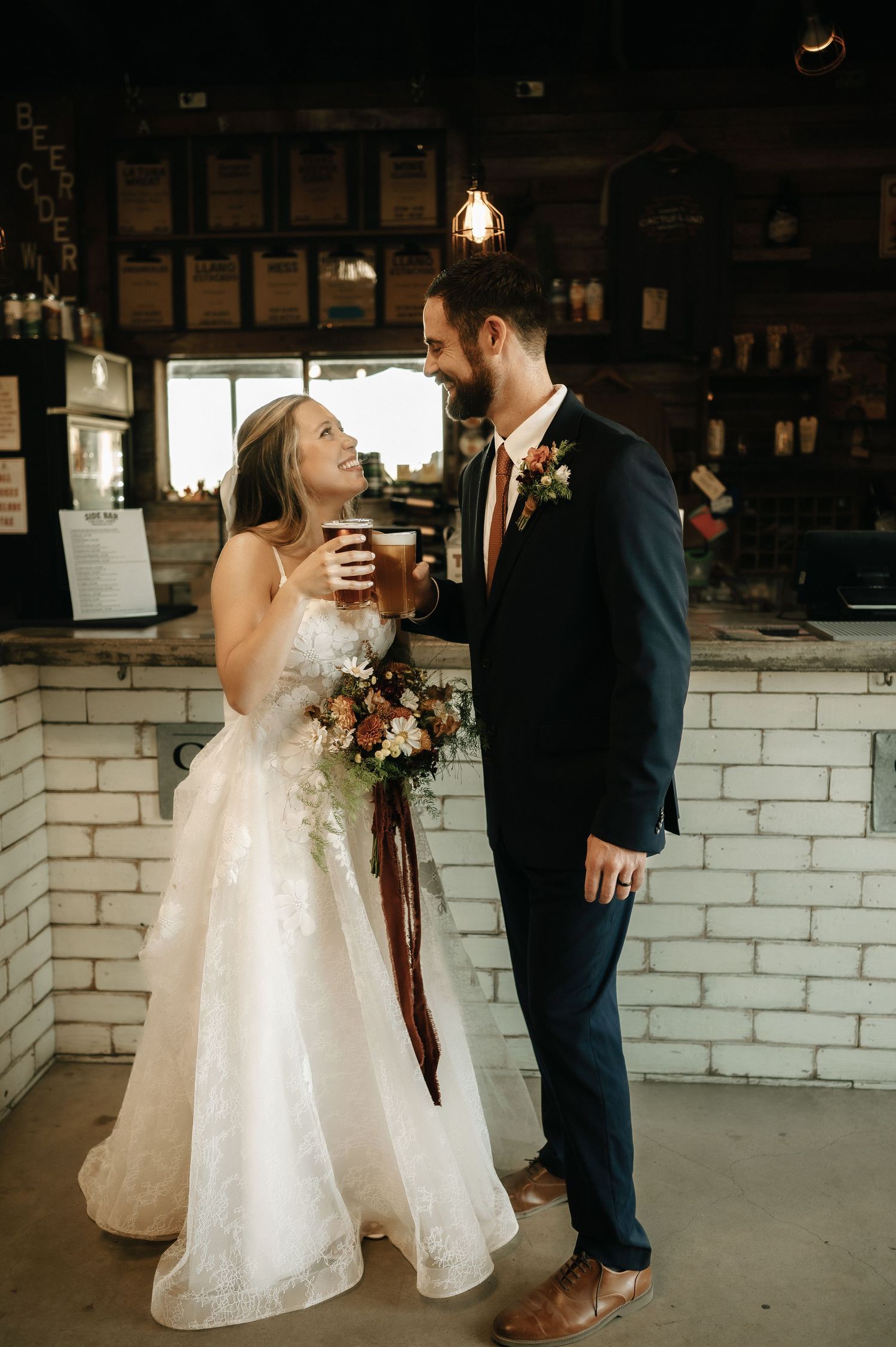 Newlyweds share intimate moments against white brick wall backdrop.