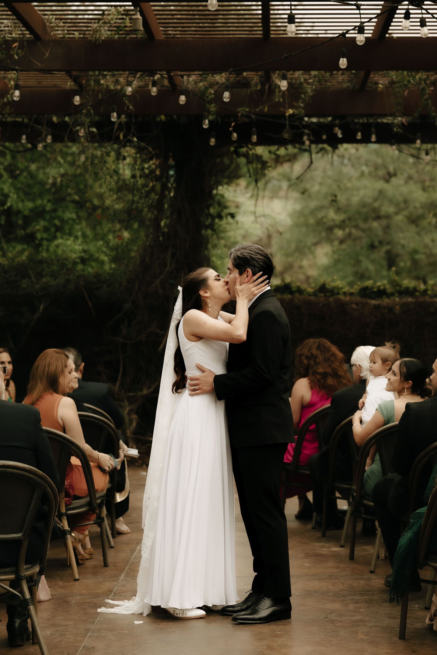 Intimate wedding ceremony takes place under a covered outdoor venue.