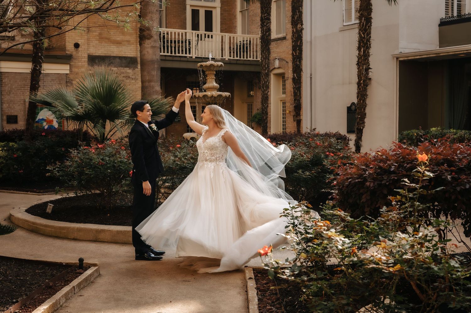 Wedding couple posing in a garden with blooming flowers.