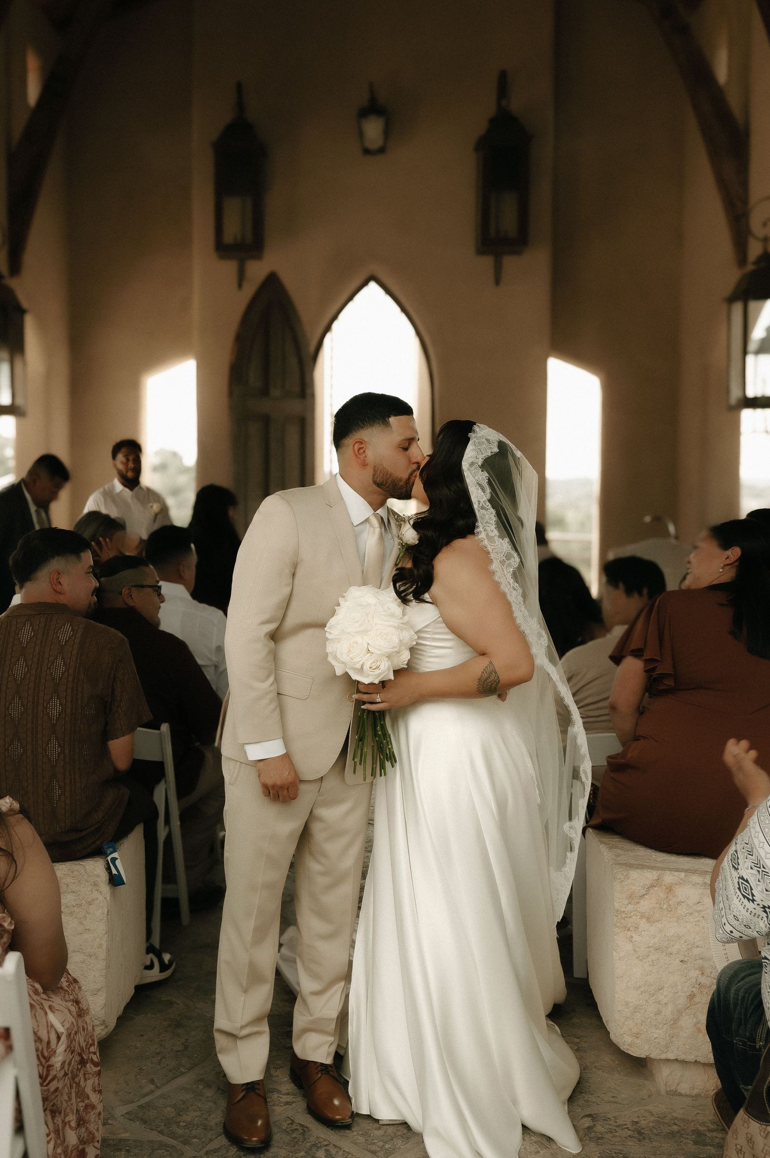 Wedding celebration inside a chapel with guests gathered around the newlyweds.