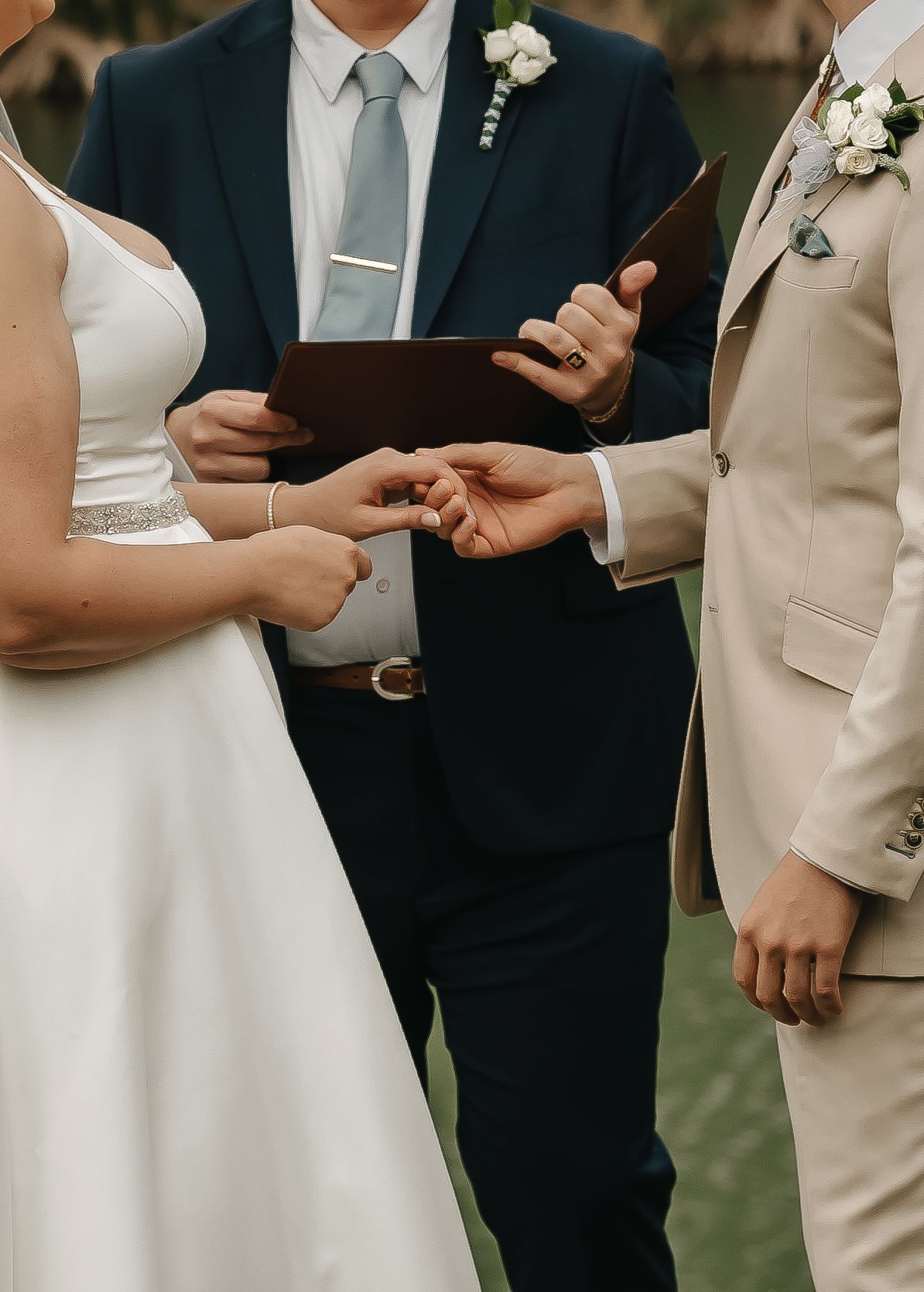 Close-up of ring exchange during outdoor wedding ceremony with officiant.