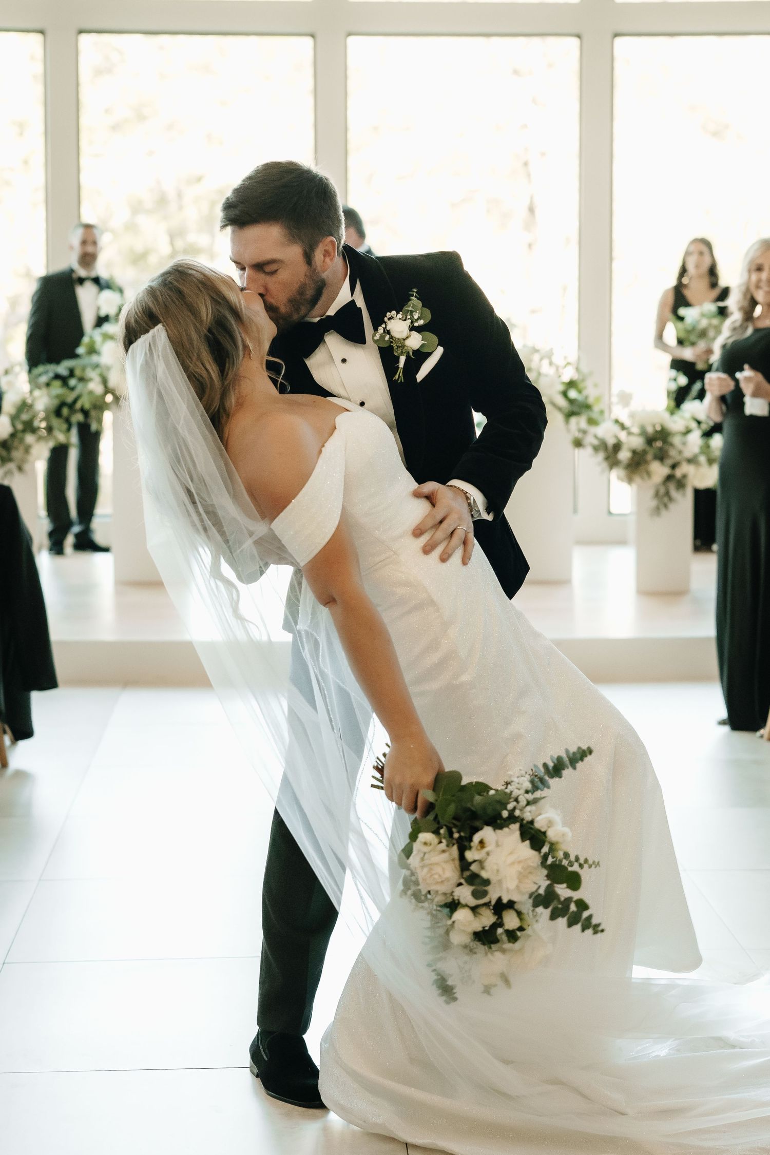 Romantic wedding dance sequence captured in a bright modern venue with floral decorations.