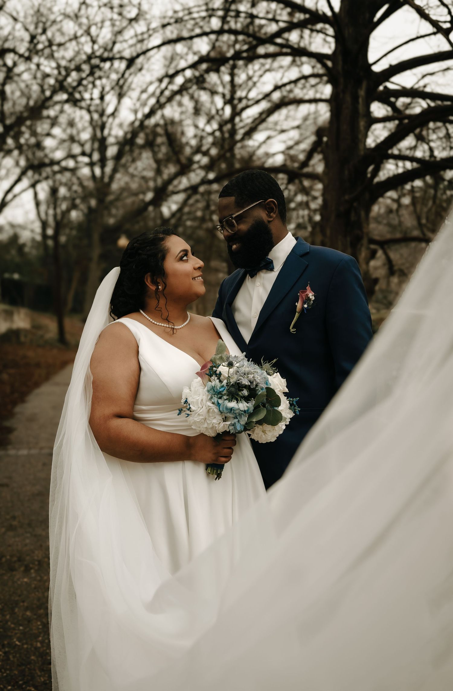 Artistic wedding photos showing flowing white dress and veil against a natural outdoor backdrop.
