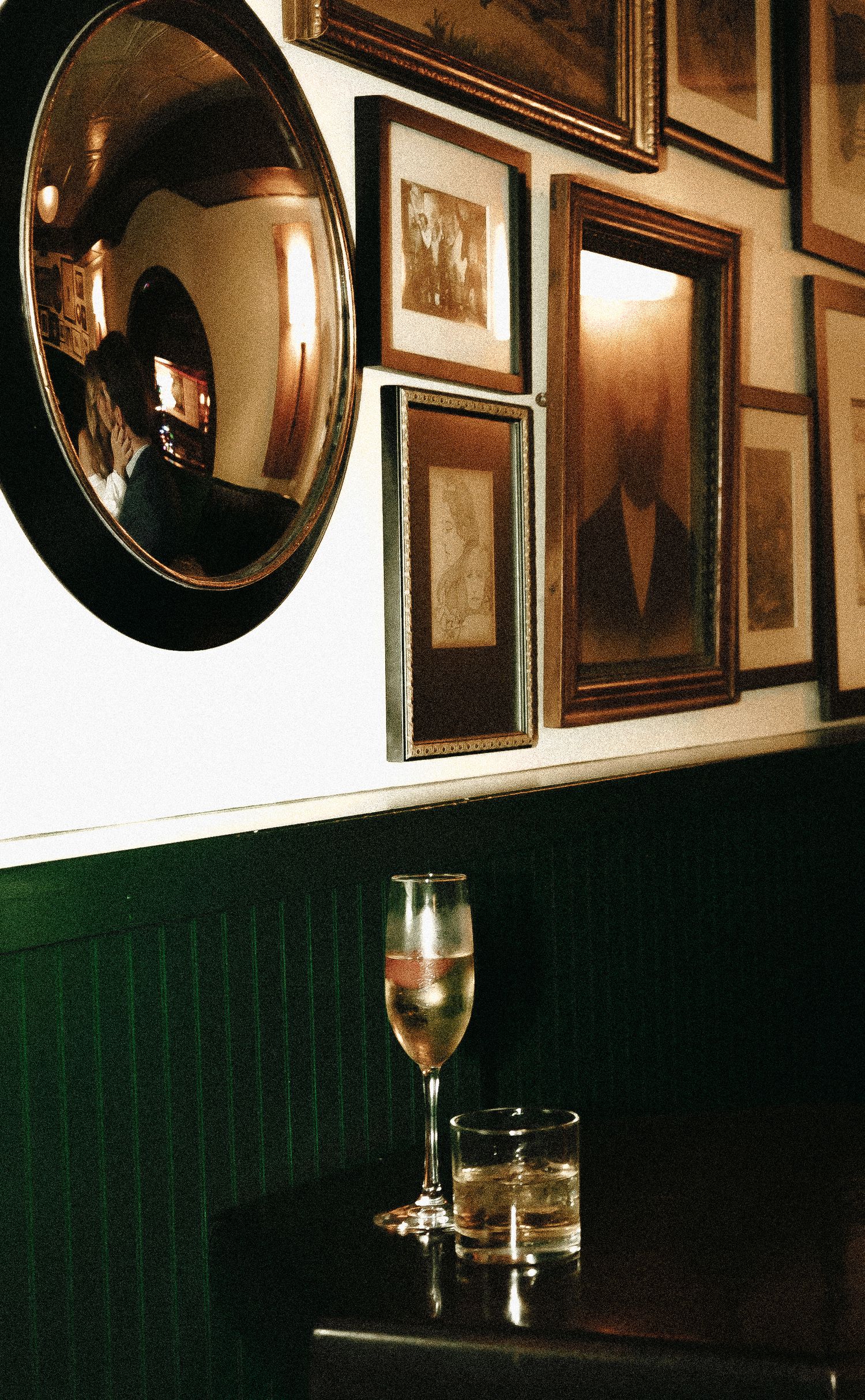 Vintage pub interior with convex mirrors and framed artwork on dark wood paneled walls.