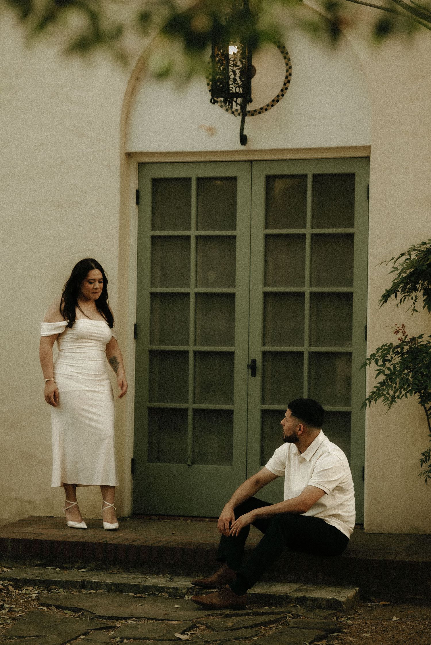 A casual engagement photo session outside a building with green windows.