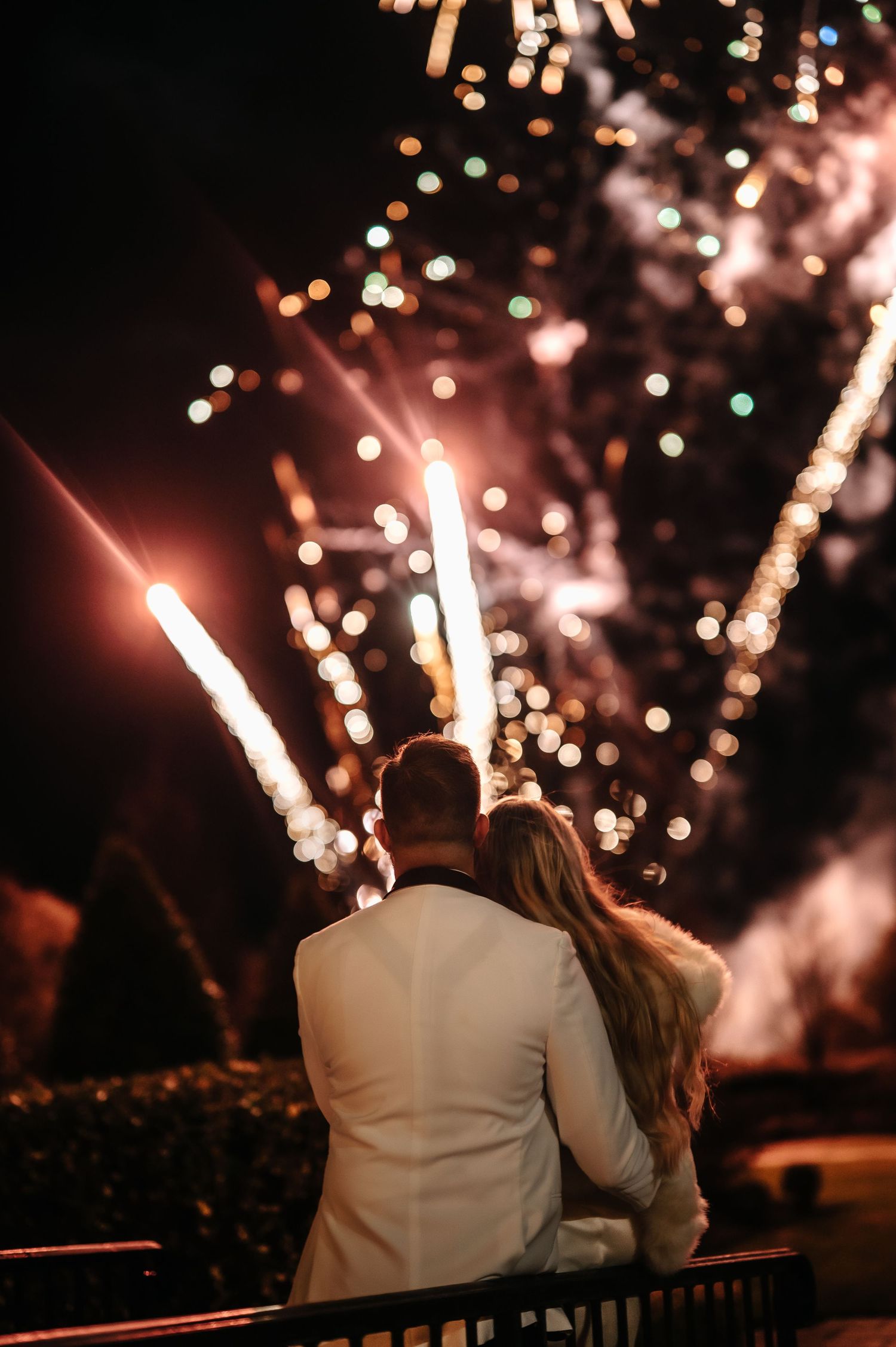 A couple watches fireworks together during their wedding celebration.