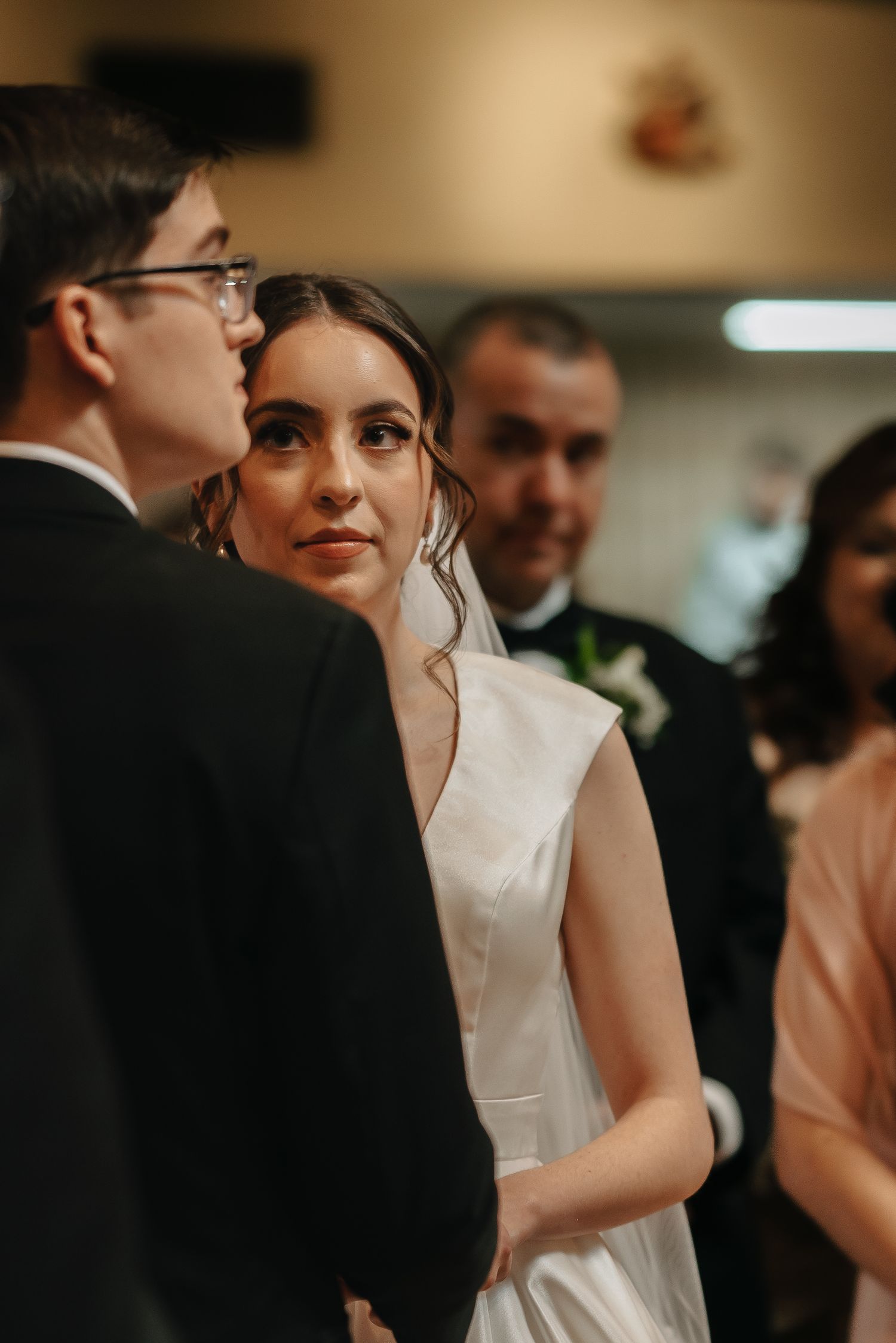 Intimate moment captured during wedding ceremony with soft lighting and formal attire.