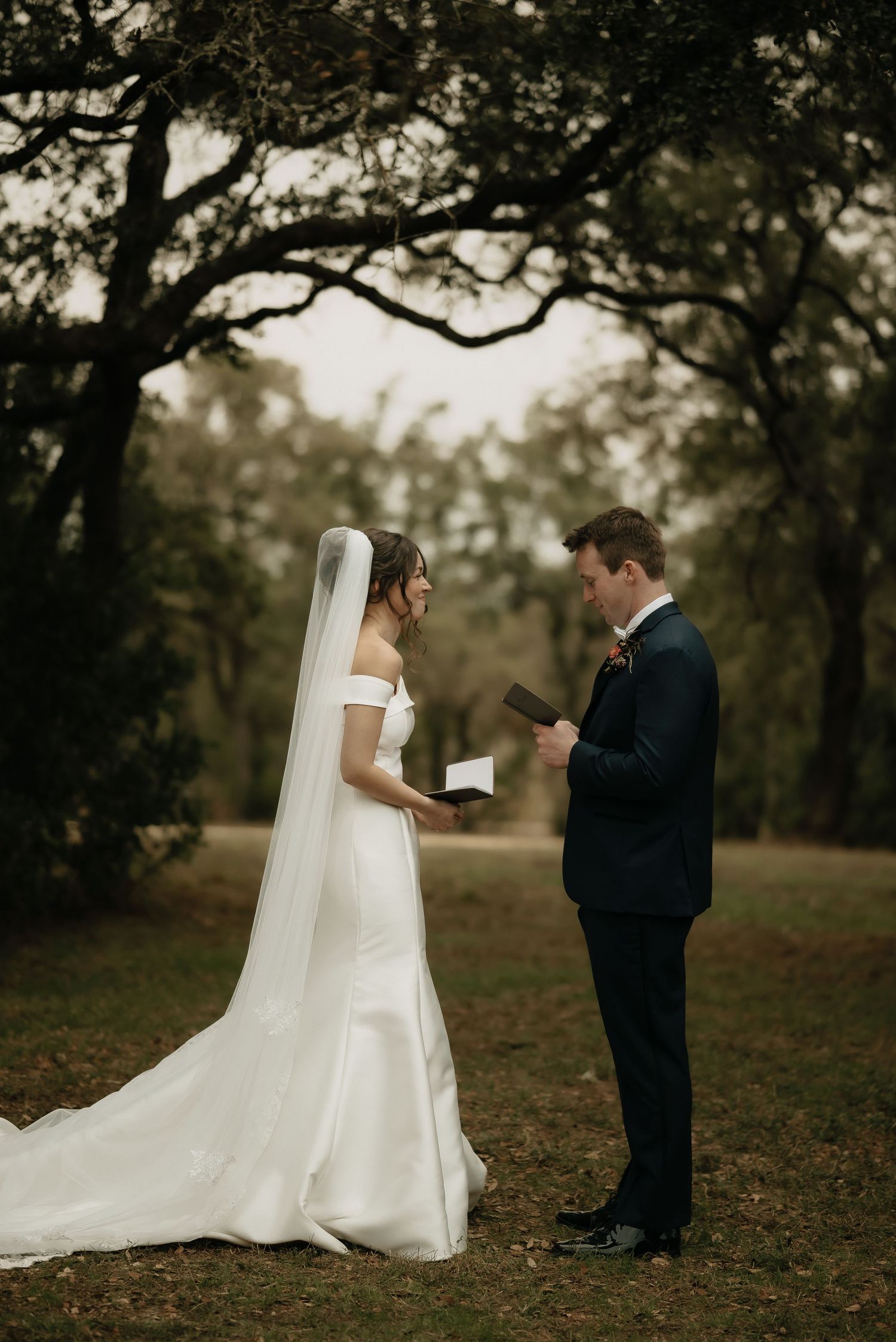 A couple exchanges vows or letters during their first look moment in an autumn outdoor setting.