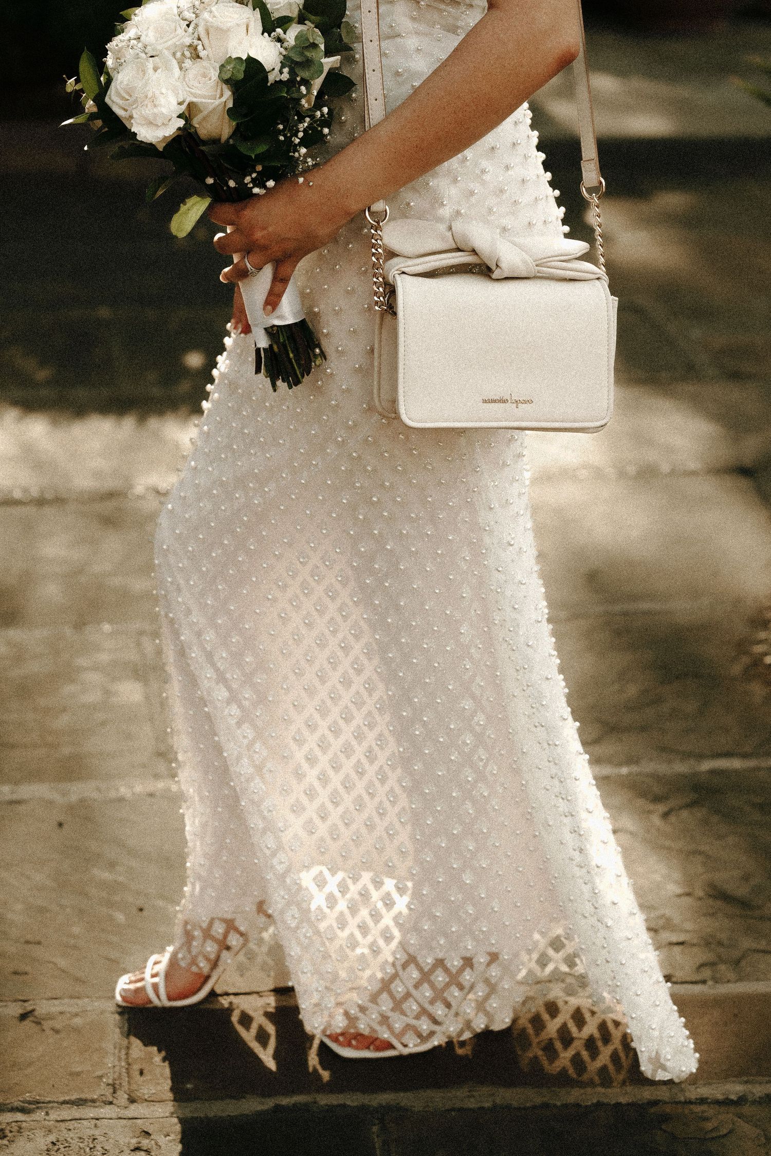 Detail shot of a textured white wedding dress with matching handbag.