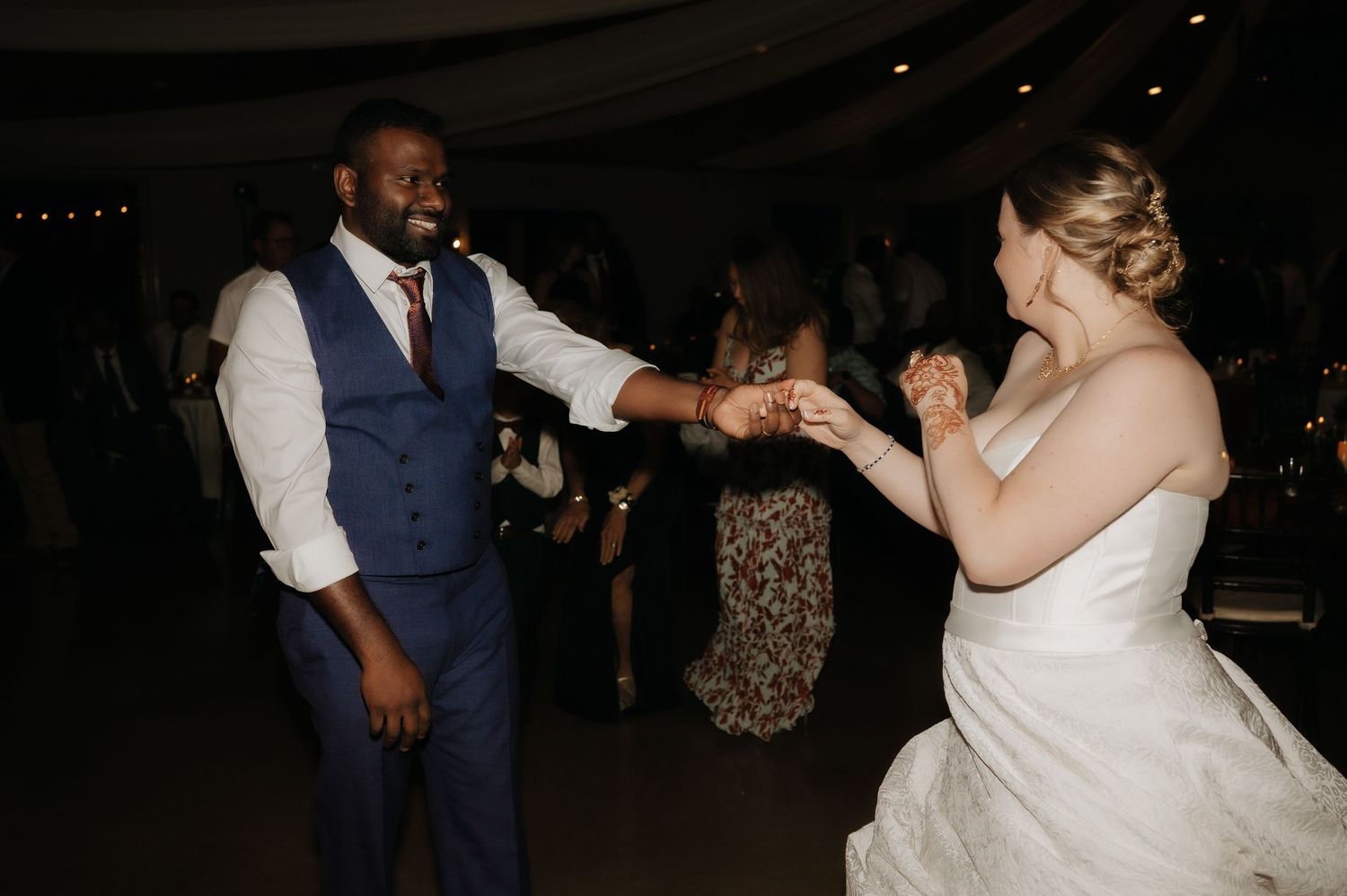 Couple dancing and celebrating during dimly lit wedding reception.