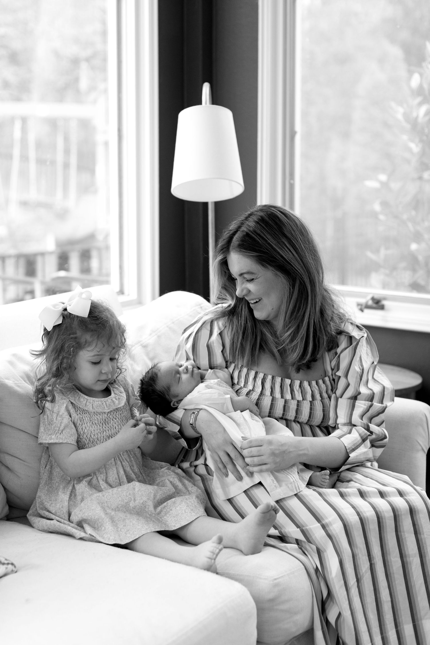 A heartwarming black and white photo of a family sharing a quiet moment on a couch by a window.