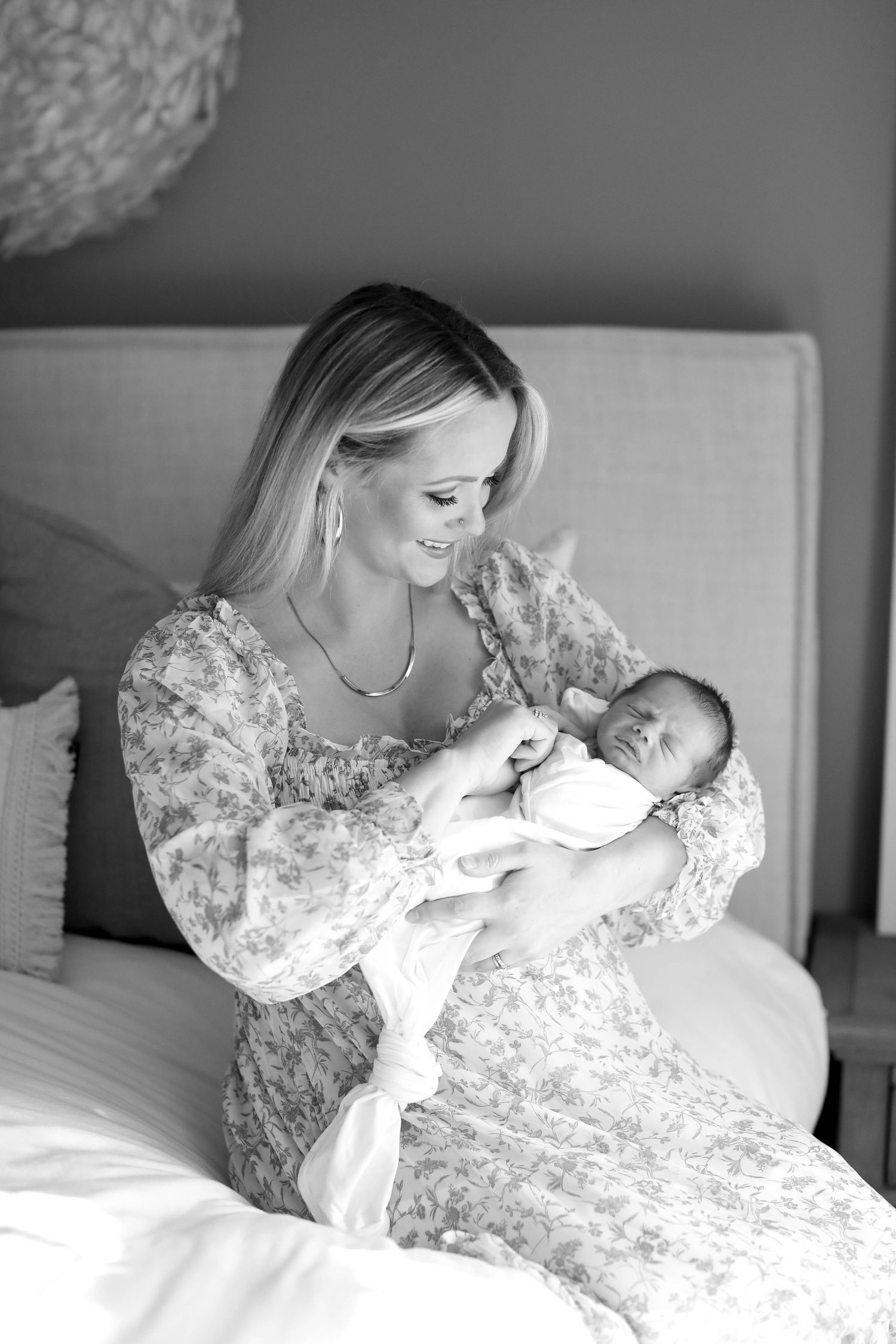 Black and white portrait of tender newborn care moment in soft lighting.