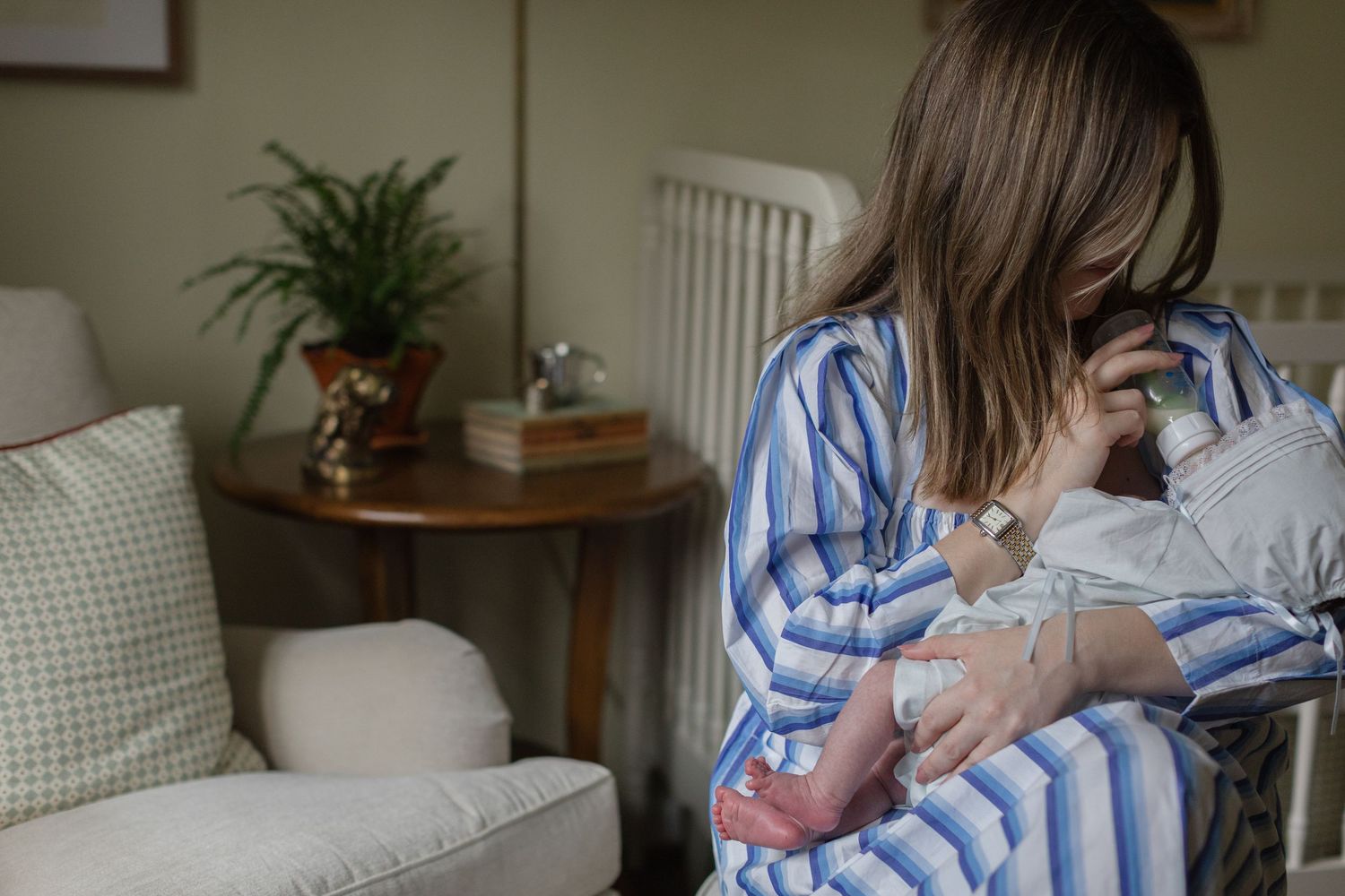 Gentle moments between parent and baby near a white crib and houseplants.